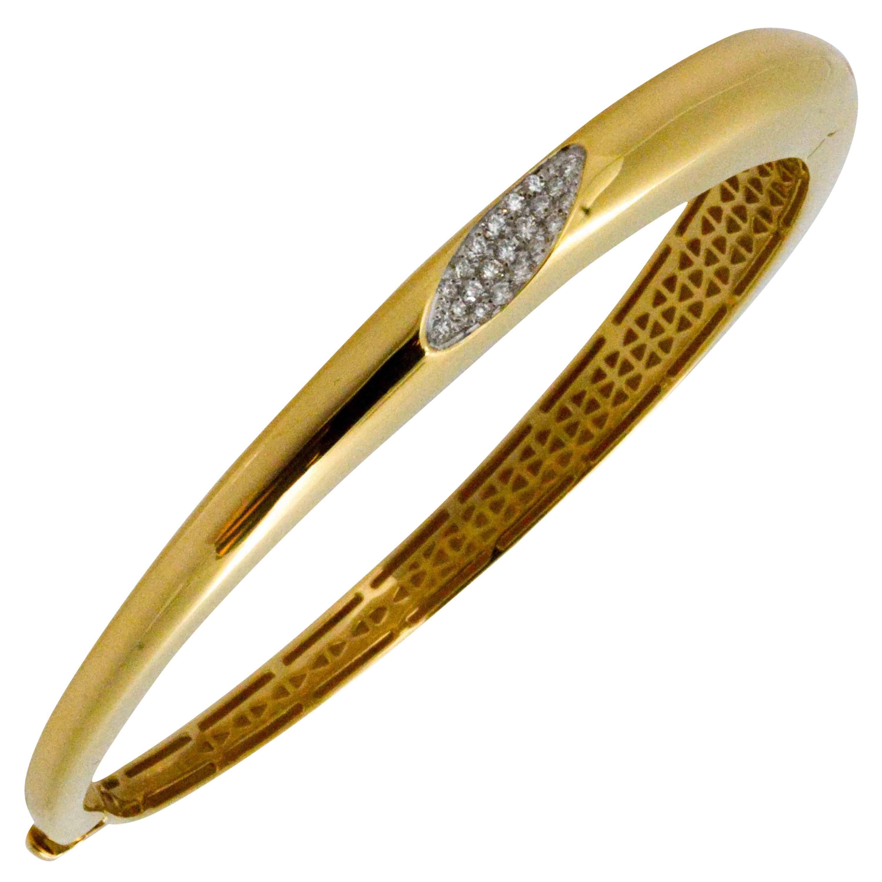 Created by Italian designer Roberto Coin with a sleek tapered shape and starring round brilliant cut diamonds, you will reach for this gold bangle bracelet every day. Crafted in 18 karat yellow gold, with intricate lattice work on the under side,