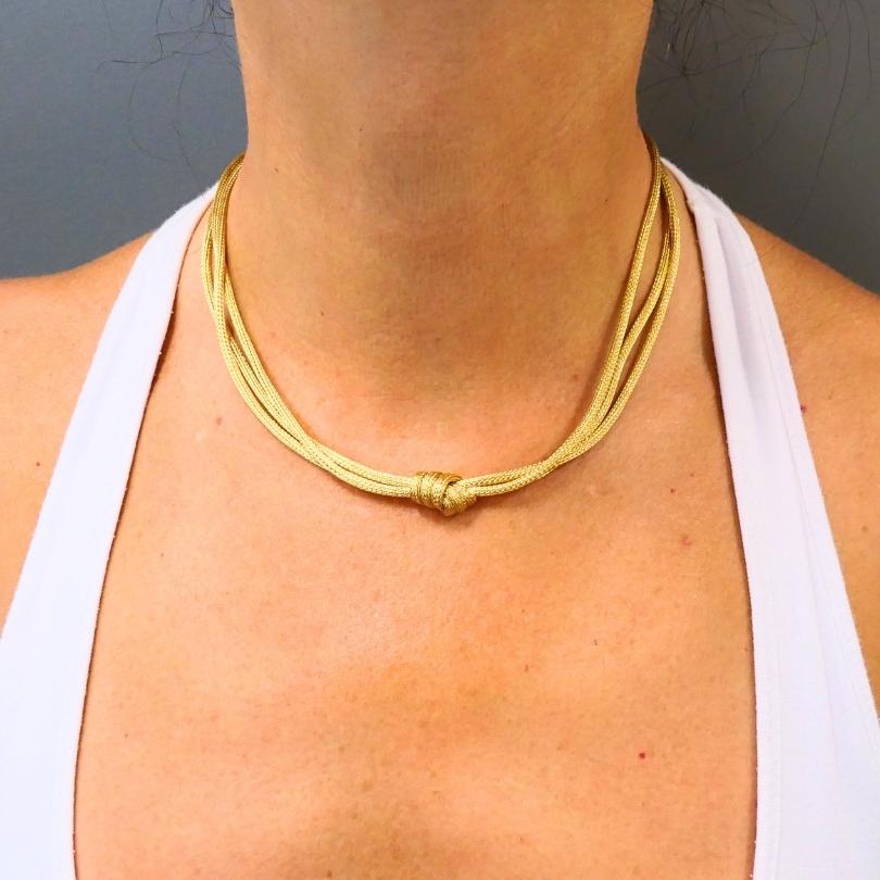 Realizzata in oro 18 carati, questa elegante collana presenta diversi fili intrecciati graziosamente a formare un nodo centrale. Il design a rete fluida offre una dichiarazione audace ma senza tempo, mentre i dettagli intricati riflettono
