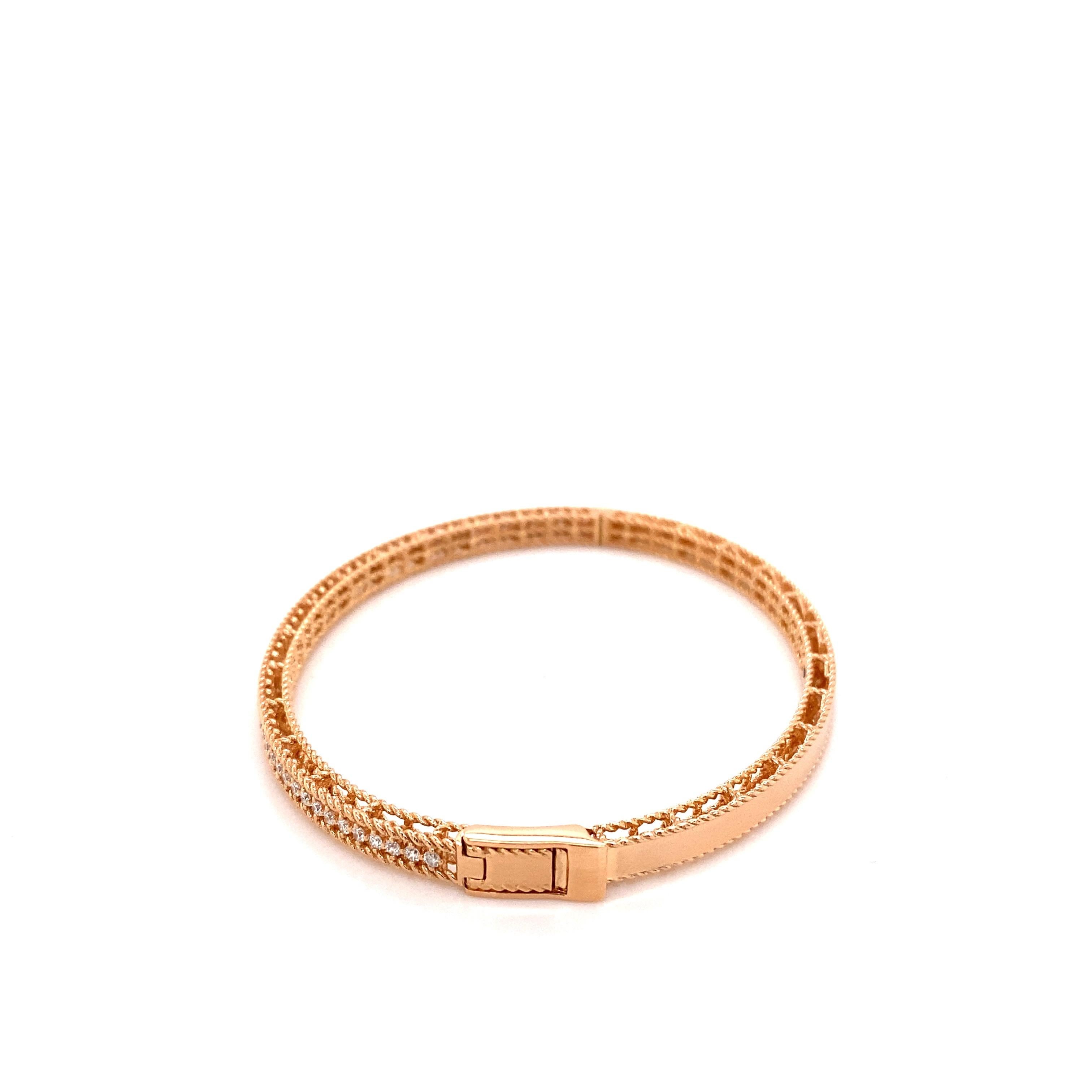 The symphony bracelet from Roberto Coin is crafted from 18 karat rose gold and features braided detailing, 0.61ct total weight in round diamonds, a small synthetic ruby set on the inside, and a hinged push-lock closure. This bracelet will fit up to