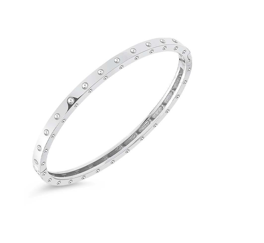 From Roberto Coin's Pois Moi Collection this elegant oval symphony bangle is made from 18K white gold. Their stylish dimpled design lines along the entirety of the bangle and the hinged edge allows easy application. Whether you wear alone or stack