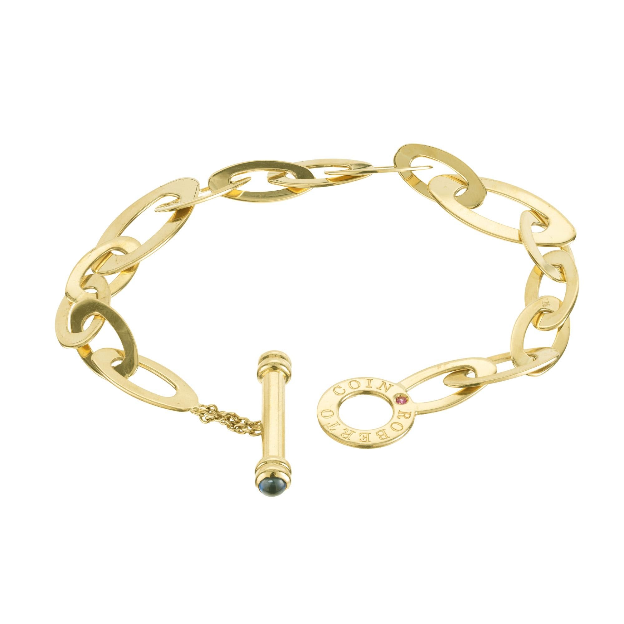 Classic oval link chic and shine Roberto Coin 18k yellow gold link bracelet. Classic Roberto Coin design. This bracelet is 7.75 inches in length. It is accented with one round red ruby and tow cabochons sapphires on each end of the bar. 

2 cabochon