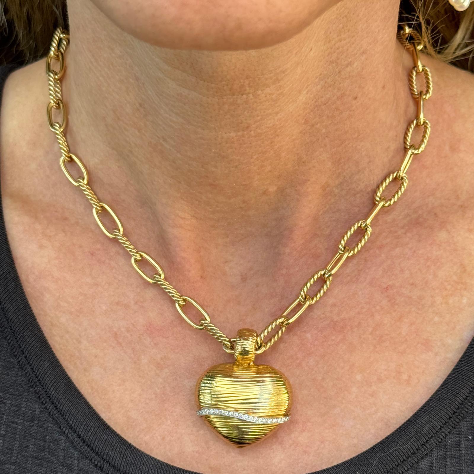 Questo affascinante ensemble di Roberto Coin è caratterizzato da uno scultoreo pendente Heart Puff in oro giallo 18 carati accentato da una linea di 26 diamanti rotondi con taglio a brillante, che aggiungono un sottile scintillio. Il ciondolo è