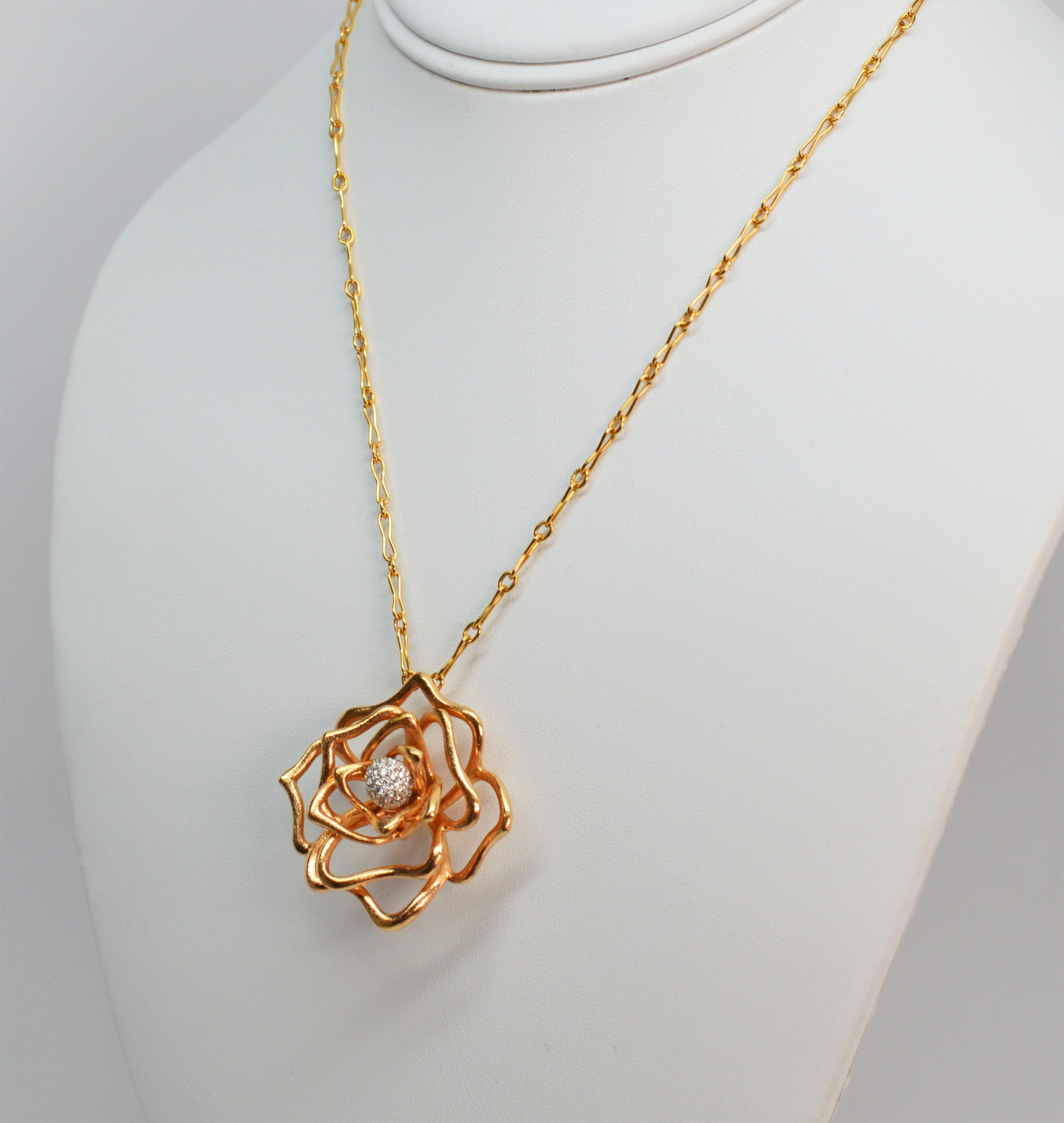 Questa collana di Roberto Coin, disegnata ad arte, raffigura una rosa dimensionale in stile libero con petali traforati in oro rosa 18 carati lucido. Il centro floreale è costituito da un gruppo di diamanti incastonati G/VS1 di poco meno di un