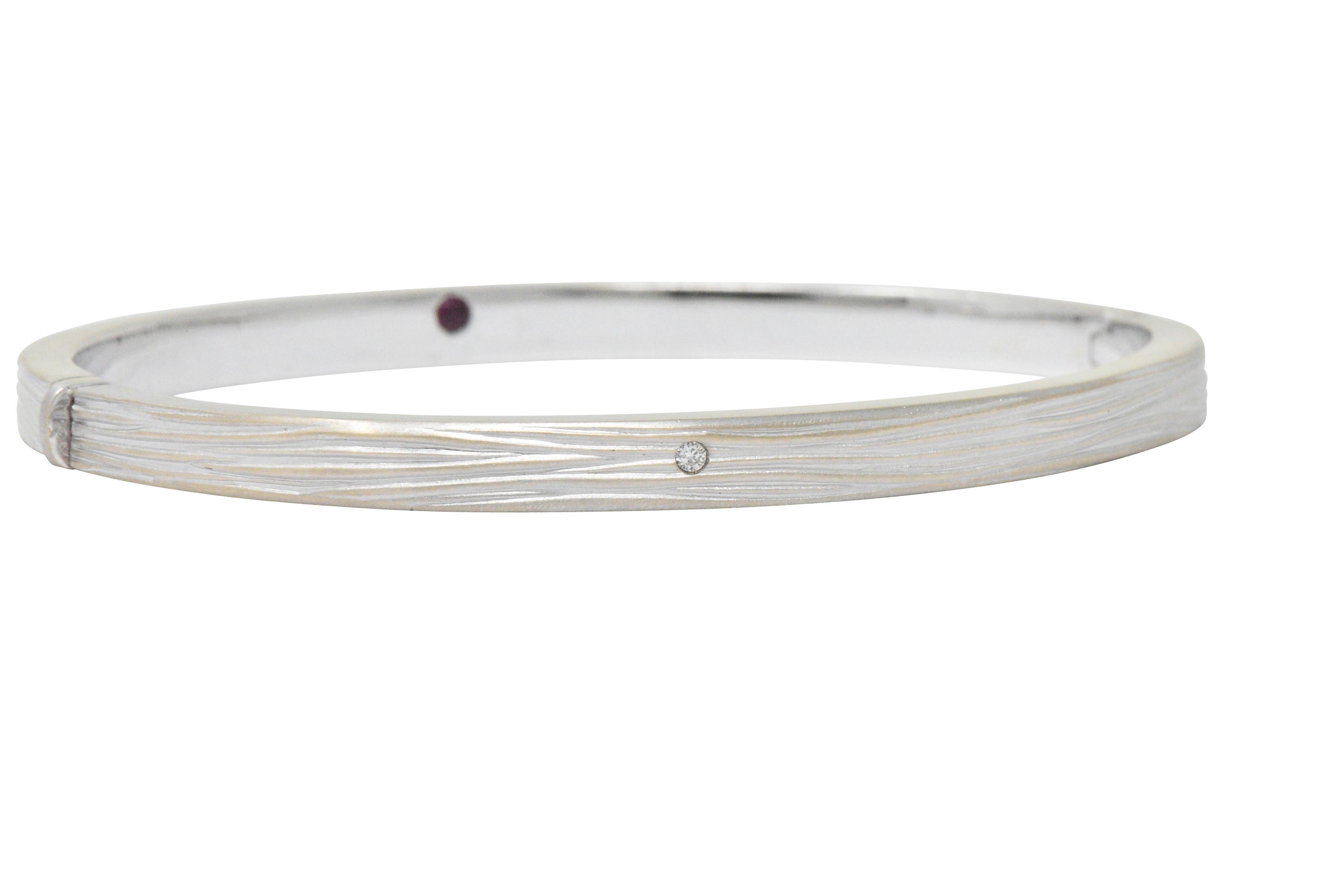 Hinged bangle style bracelet featuring wrinkled elephant skin texture and matte finish

Flush set to front with a subtle round brilliant cut diamond accent weighing approximately 0.01 carat; eye-clean and white

Completed by concealed clasp and