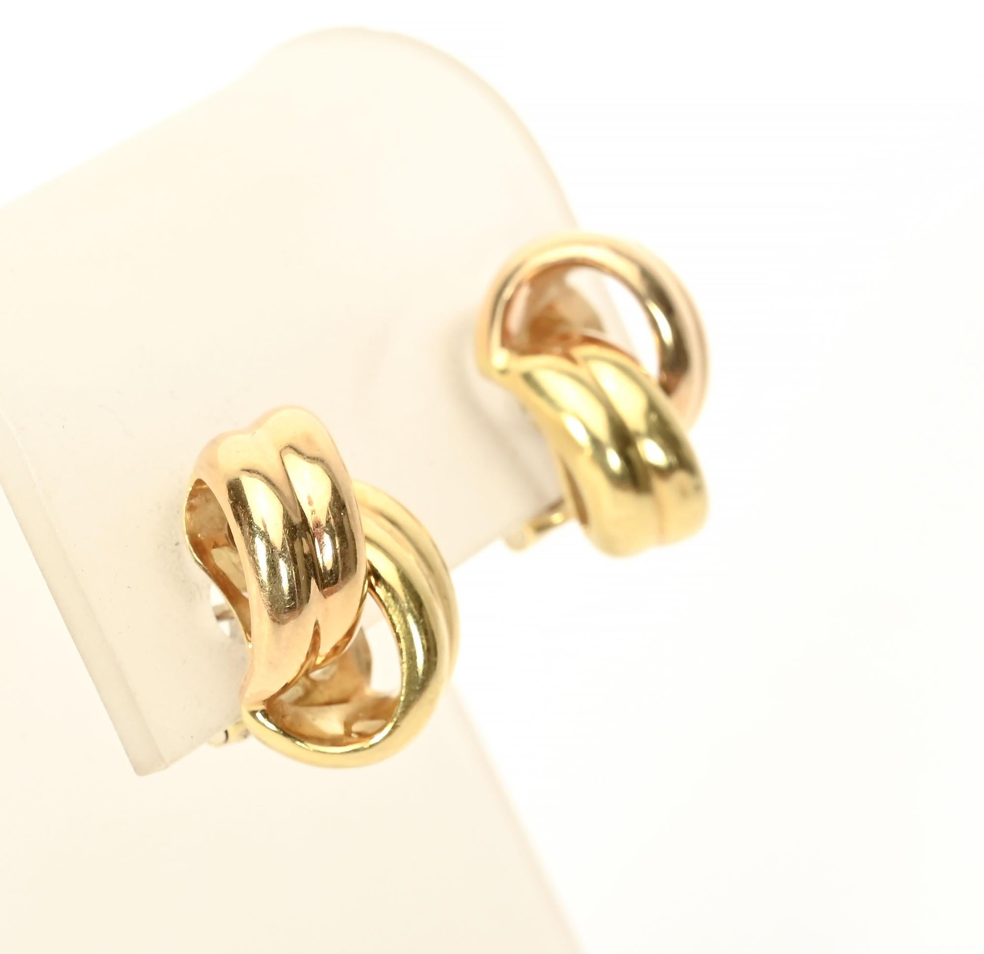 Double loop earrings in 18 karat gold by Roberto Coin. The huggie size earrings have an two loops that intertwine with each other. Backs are posts and clips. The earrings measure 5/8