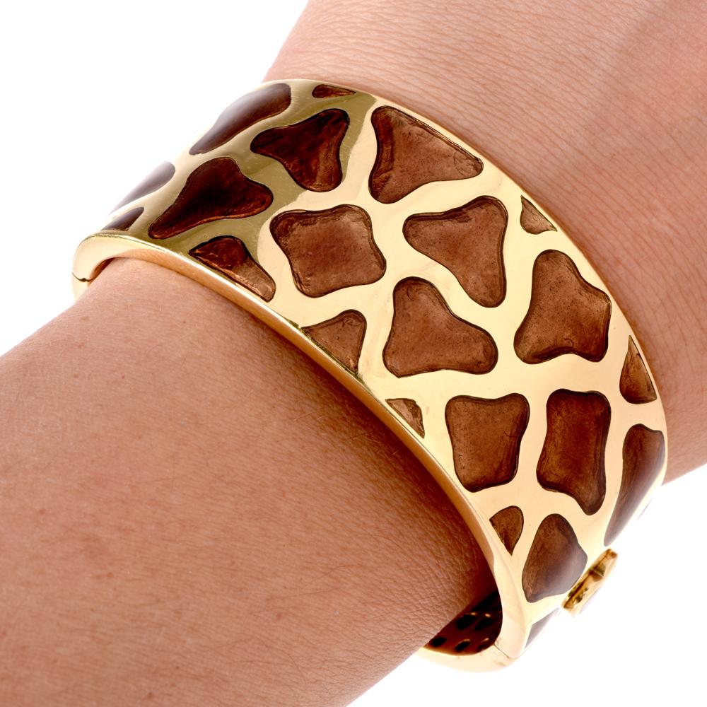 This authentic Roberto Coin giraffe print enamel bangle bracelet is crafted in solid 18 karat yellow gold, weighs 100.50 grams and tapers in width from approx. 1 1/4 inches at the front to approx. 1/2 inch at the back. Embellished with brown enamel