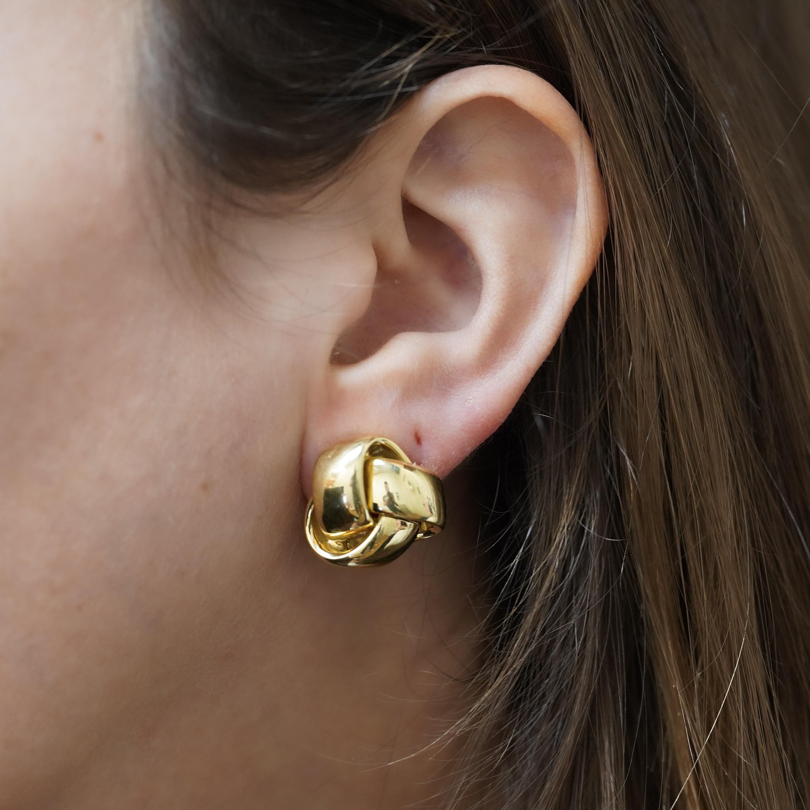 Pendientes de clip de oro amarillo de 18 quilates Roberto Coin con un diseño de nudo entrelazado y sistema de cierre de palanca. Estos pendientes de fabricación italiana miden 19x18 mm y pesan 12,8 gramos, y están diseñados tanto para orejas