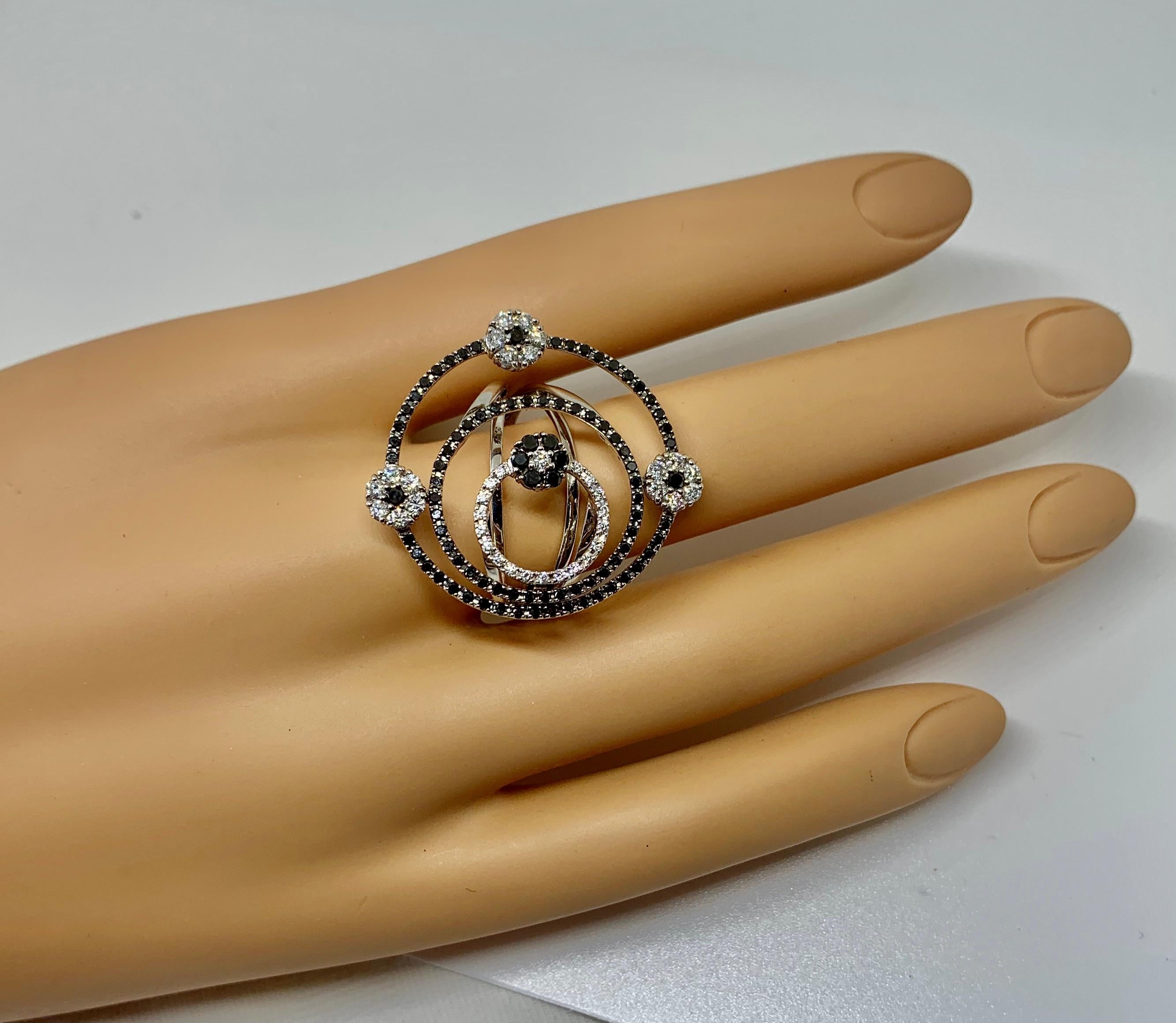 This is a stunning and rare ring by Roberto Coin in a circle flower motif design with Black and White Diamonds in 18 Karat White Gold.  The fabulous ring is large and dramatic and is a very rare Roberto Coin piece.  The design is just spectacular