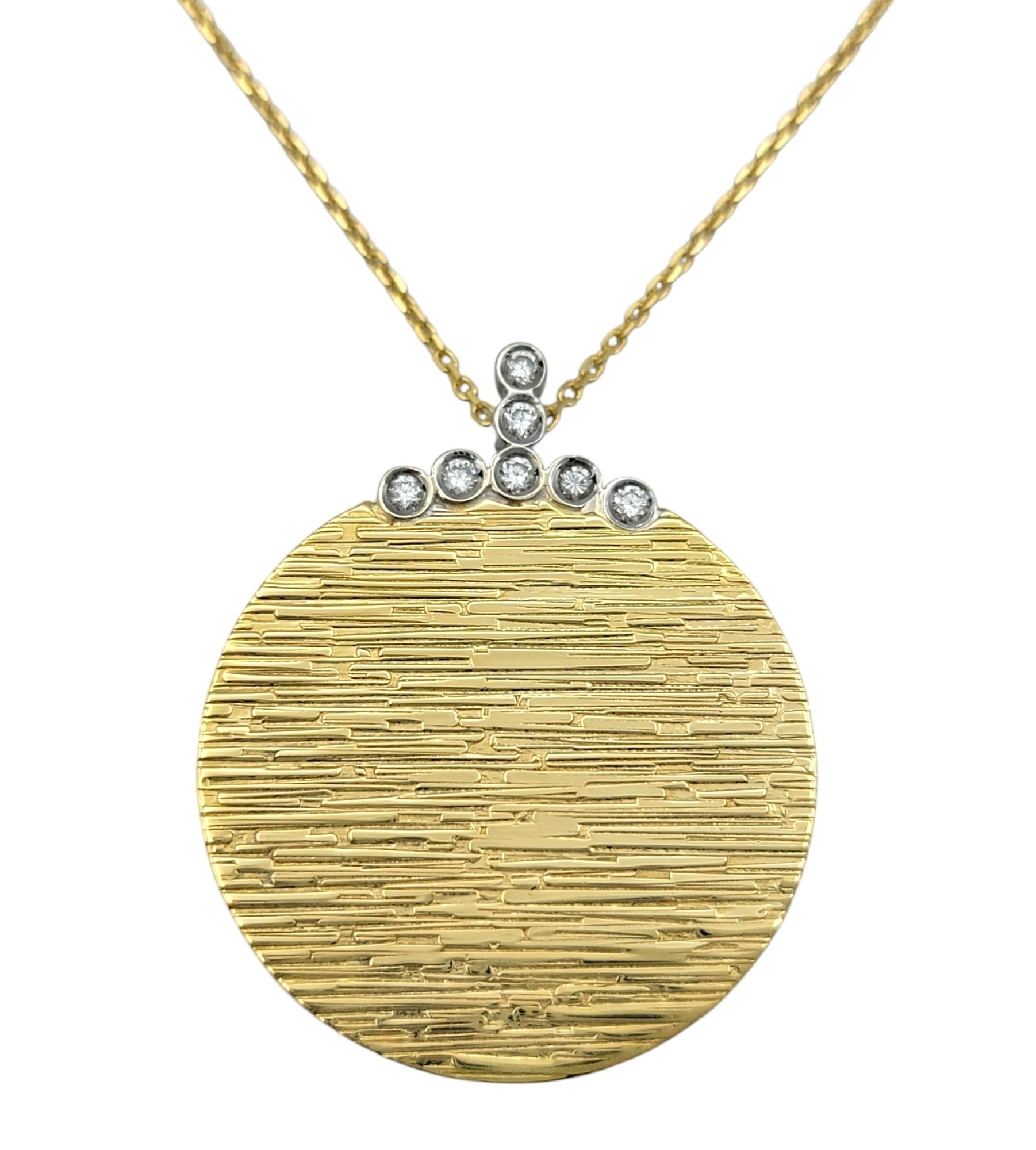 Incarnant un luxe discret, cet authentique pendentif disque Roberto Coin est une expression intemporelle d'élégance raffinée. Réalisé en or jaune 18 carats rayonnant, le disque en or brossé dégage une texture sophistiquée, rehaussée par une délicate