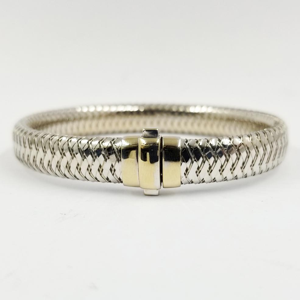 This flexible 18 karat white gold bracelet is from the Roberto Coin Primavera Collection. The 9mm wide bracelet design is comprised of woven gold around a central flat tube. The inside of the double pusher clasp is stamped 