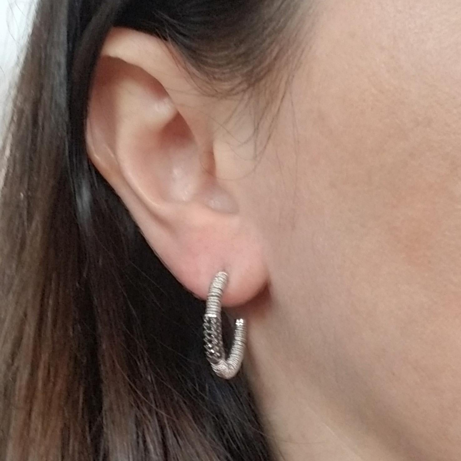 18 karat white gold hoop earrings from designer Roberto Demeglio's Joy Collection. Each earring features multiple textured white gold rings that spin freely around the center wire, and pave set black diamonds. The total weight of the black diamonds