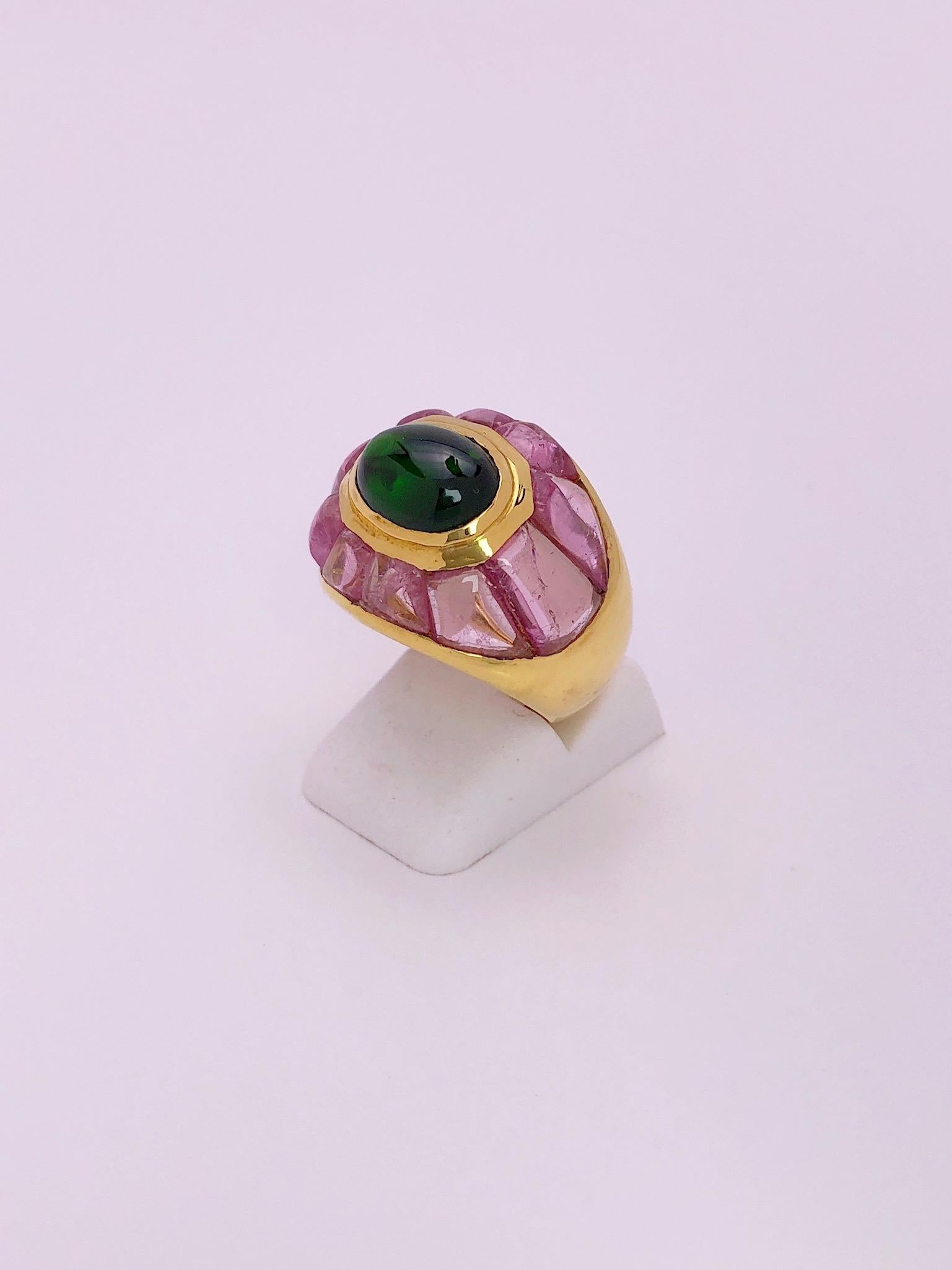 Questo anello in oro giallo 18 carati, realizzato da Roberto Legnazzi, è incentrato su un cabochon ovale.  tormalina verde. Il bordo a gonnellino è incastonato con un entourage di tormaline rosa di taglio fantasia.
Timbrato Italia 18kt
Anello misura