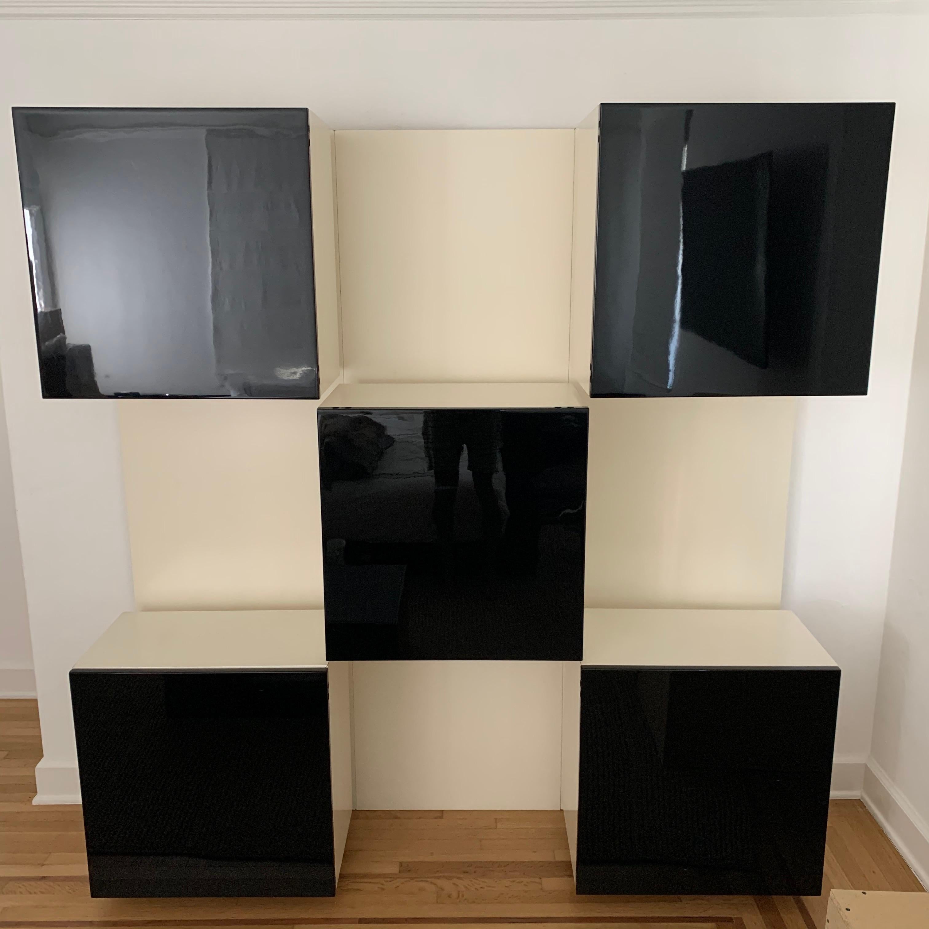 wall-mounted shelving and storage unit, illuminated and backlit creating intriguing lighting for displayed pieces as well as functional lighting for the items inside the cabinets. Rendered in a matte white frame and case with 5 gloss black lacquered