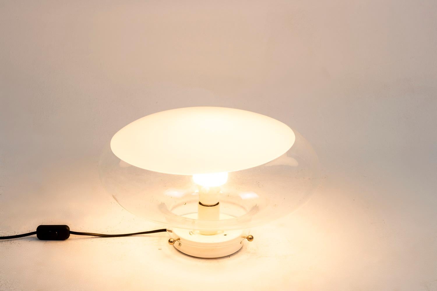 Roberto Pamio, attributed to.
Leucos, edited by. 

Lamp in the shape of a flattened sphere in white and transparent glass. 

Work realized in the 1960s. 

New and functional electrical system.

 