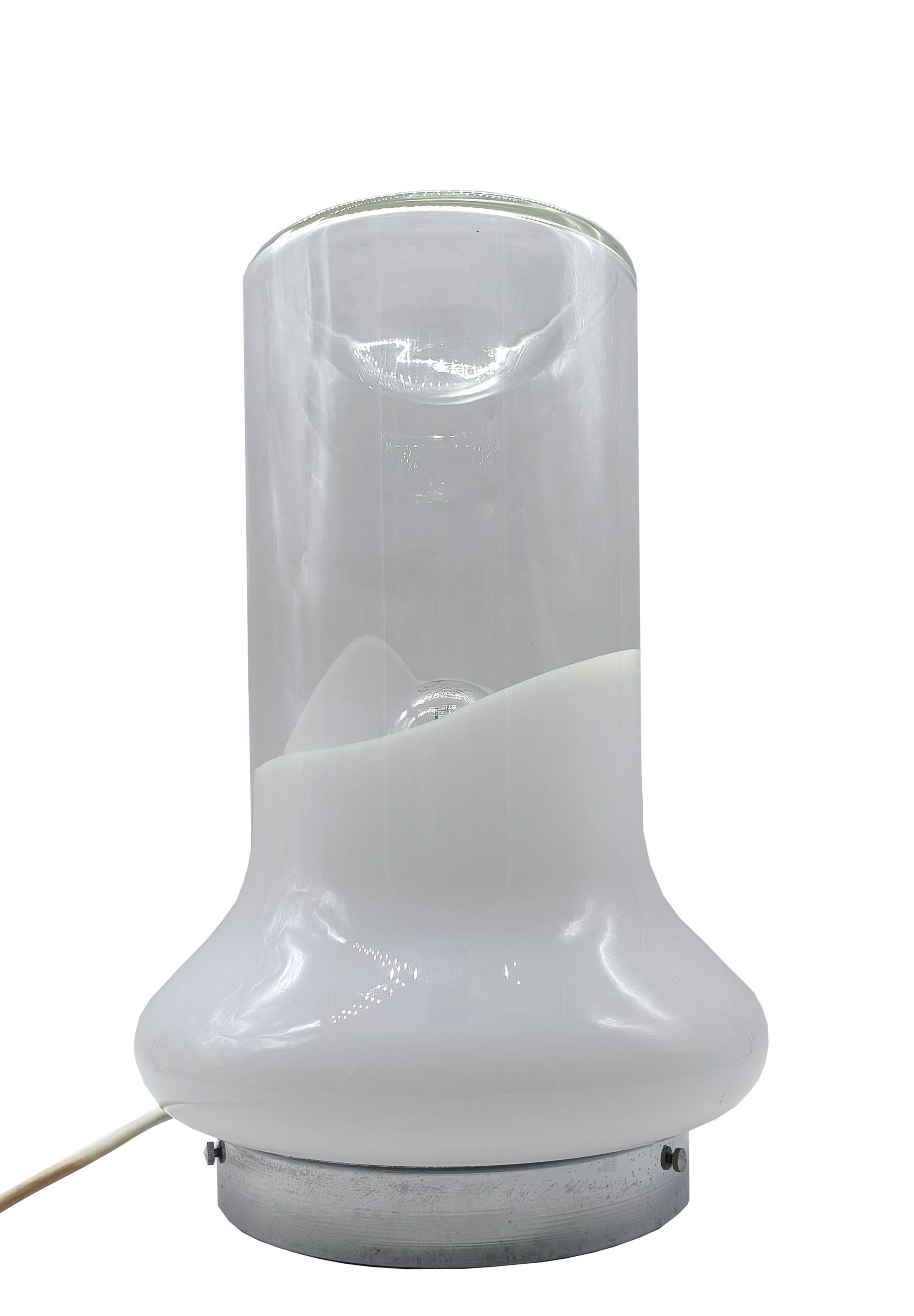 Lampada da tavolo in vetro soffiato di Murano,   con la base in vetro lattiimo e la parte superiore in vetro trasparente. La base e' in metallo cromato. Disegnata da Roberto Pamio negli anni 70 per la Ditta Leucos.
