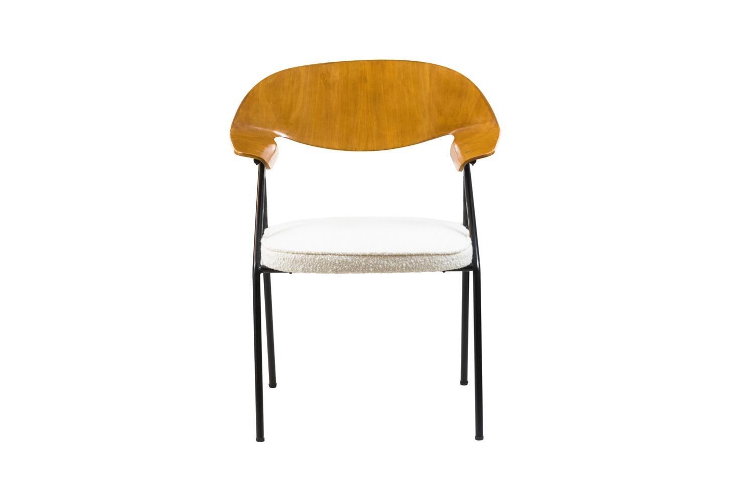 Robin day, in the style of.
Armchair standing on black lacquered tubular metal legs in reversed V-shape.
High back in molded plywood curved to obtain a curved back moving forward to the legs and forming two curved shape arms.

Trim entirely
