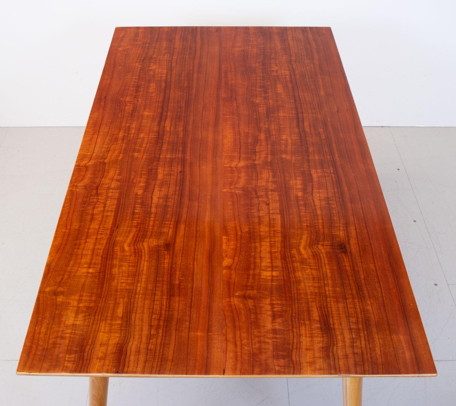 Beautiful dining table designed by iconic British designer Robin Day for Hille in 1952. This minimalist design has a beech frame and turned legs with a plywood top veneered in a vibrant Nigerian cherry wood.