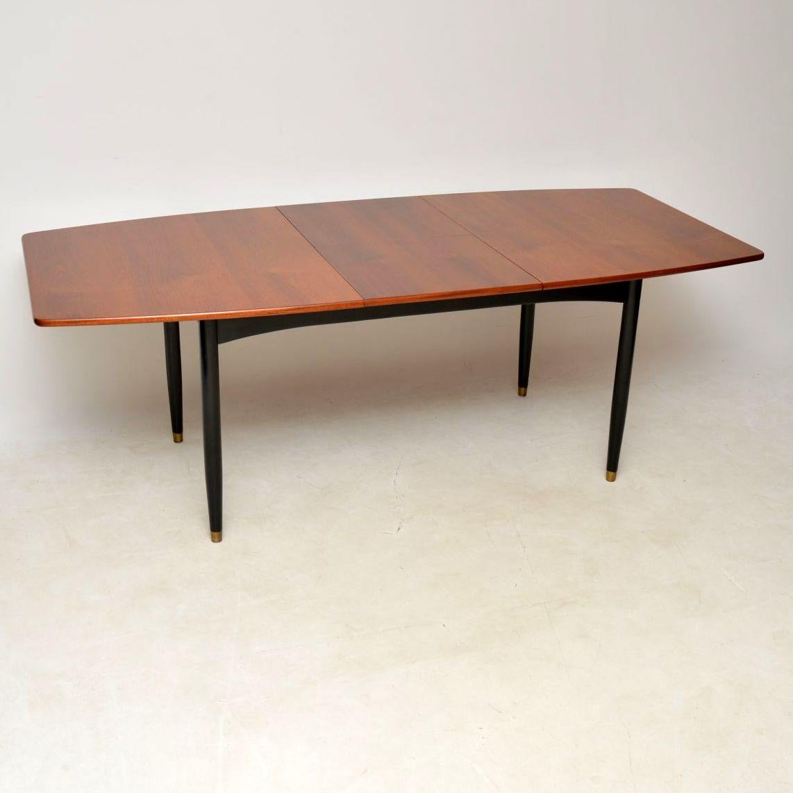 An exceptionally rare and high quality dining table, this was designed by Robin Day and made by Hille in the 1950-60’s.

This has a mahogany top and ebonized wooden legs, with brass feet caps. There is an extending leaf that unfolds from beneath