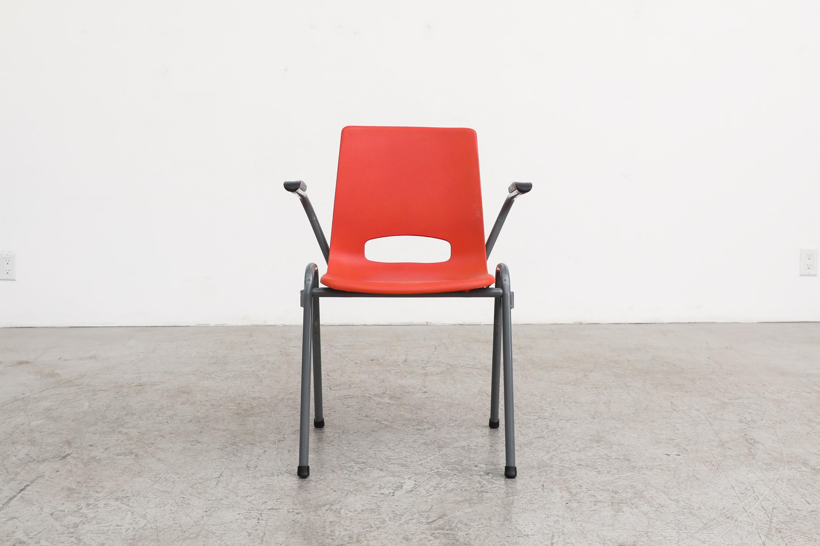 Fauteuils empilables en plastique rouge, inspirés de Robin Day, avec assise en acrylique moulé et pieds en métal émaillé gris. En état d'origine avec une usure visible, y compris des rayures sur les sièges et les cadres. L'usure est conforme à leur