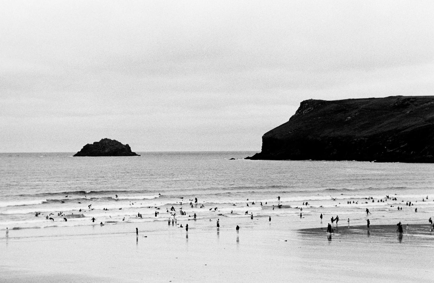 Robin Rice Black and White Photograph – Tiny Surfers in the Celtic Sea, Polzeath, England, UK, 2010