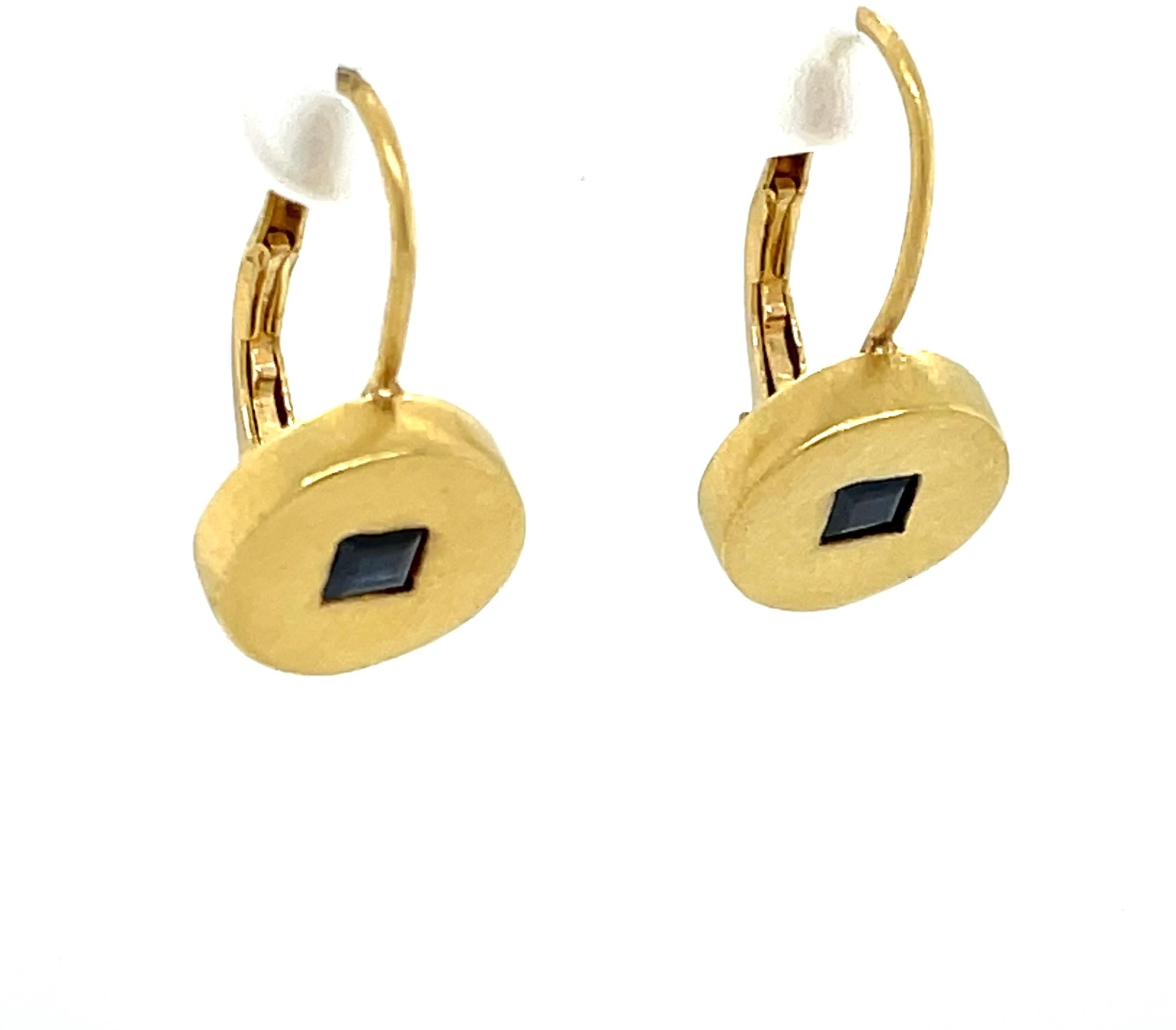 Understated, 3/8 inch round satin finished 18 karat yellow old drop earrings, each with a .15 carat emerald cut blue sapphire center accent, 30 carat total weight and a 5/8 inch drop. Simple sophistication by design from the late New York Jewelry