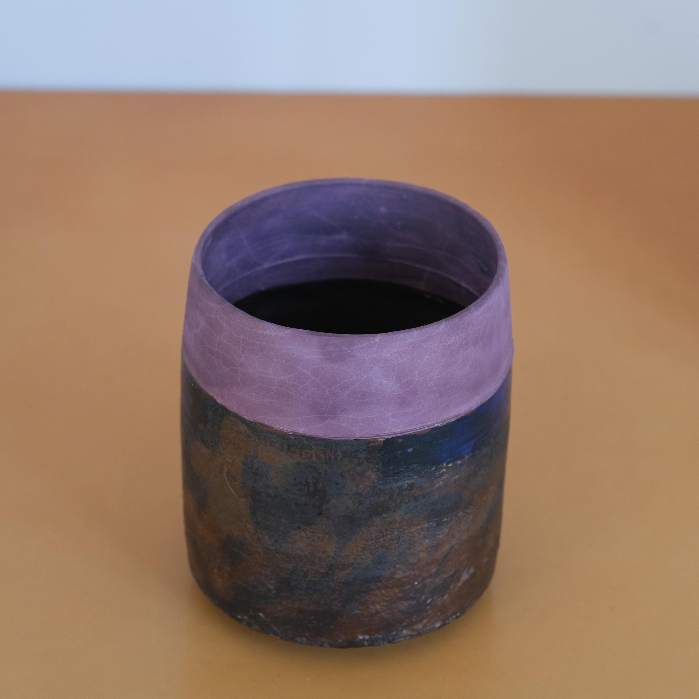 Robin Welch

Vase

Zylindrische Keramikvase, der obere Teil mit einem violetten, matten Überzug, der untere Teil mit einem braunen und schwarzen Überzug.
Darunter gestempelt mit den Initialen 