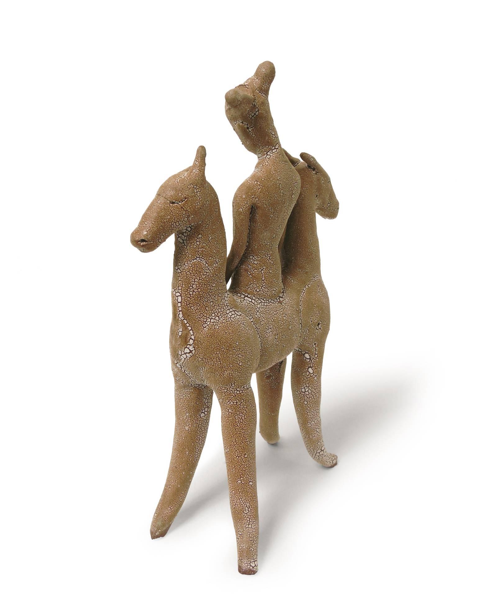 This version of Robin Whiteman's Horse Goddess measures under 7 inches tall and features a horse with two head-ends with a female figure centered between them. It is made of terracotta with a crackled white glaze. It has the look of an aged