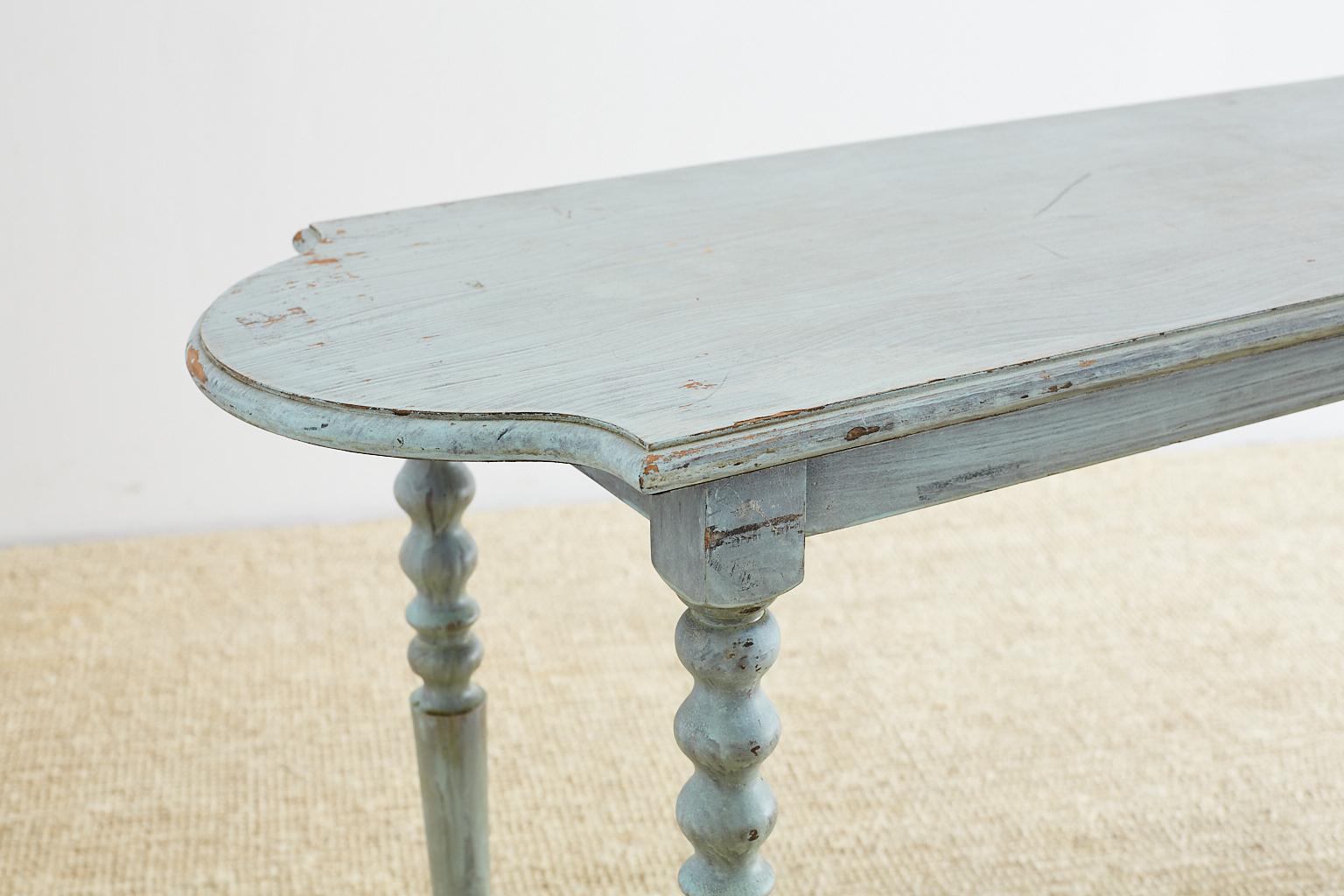 Vintage console or sofa table featuring a distressed painted finish in a lovely robin's egg blue color. Rounded on both ends and supported by thin turned legs conjoined with a stretcher.