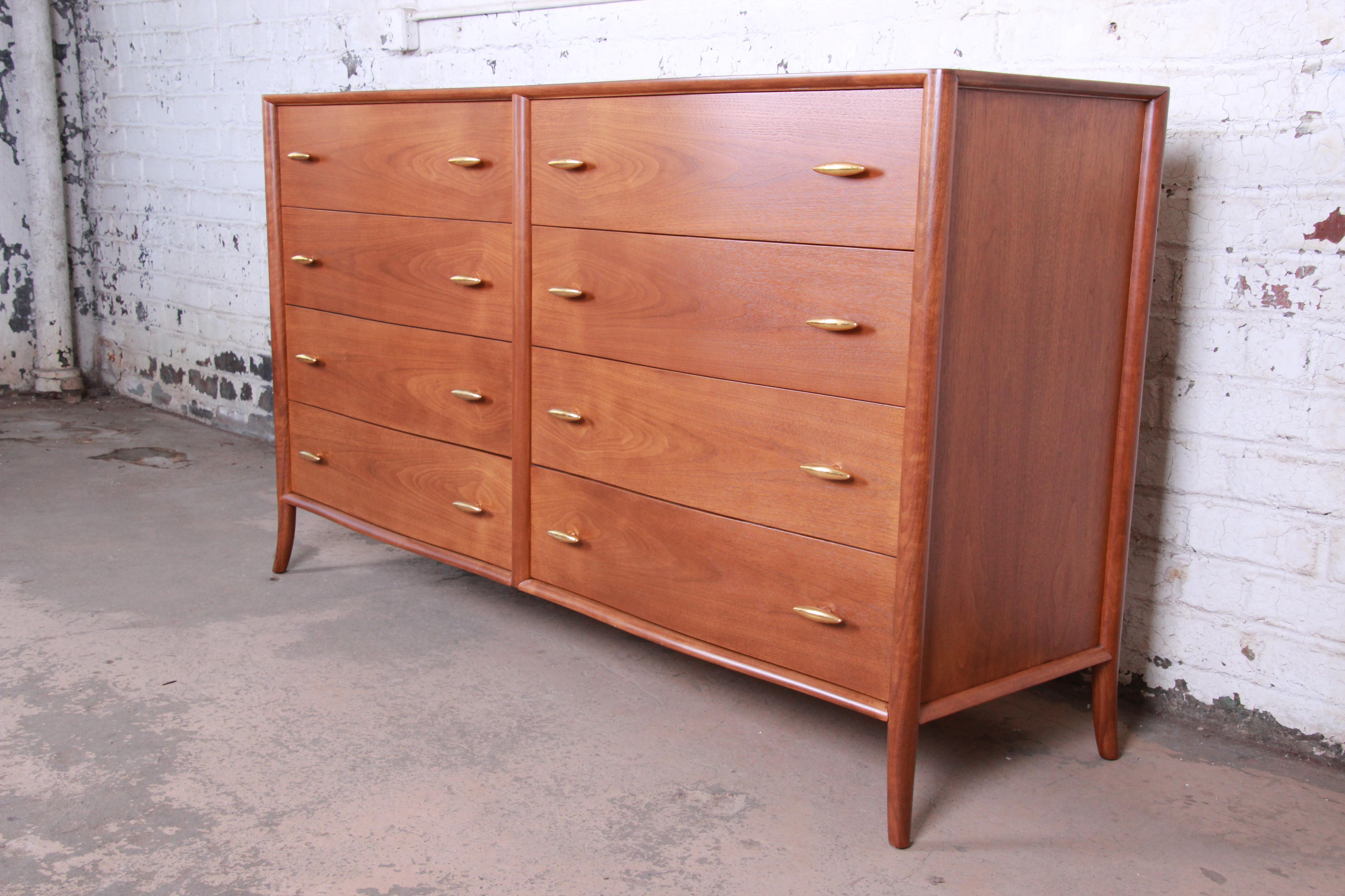 An extremely rare and exceptional Mid-Century Modern sculpted walnut saber leg double dresser designed by T.H. Robsjohn-Gibbings for Widdicomb Furniture of Grand Rapids, circa 1955. The dresser features stunning walnut wood grain with sculpted solid