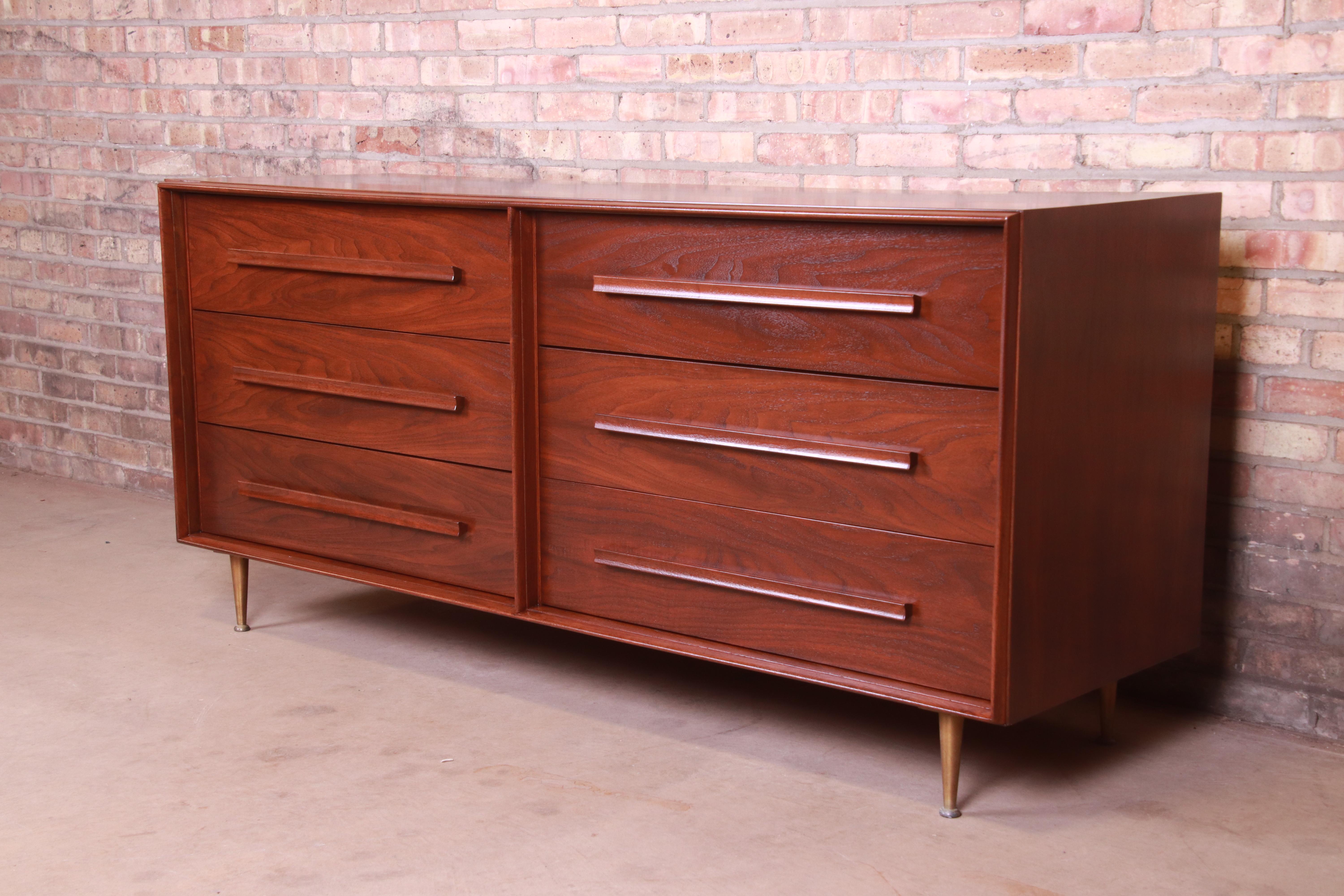 An exceptional Mid-Century Modern six-drawer long dresser or credenza

By T.H. Robsjohn-Gibbings for Widdicomb

USA, 1950s

Book-matched walnut, with sculpted walnut drawer pulls and brass legs.

Measures: 68