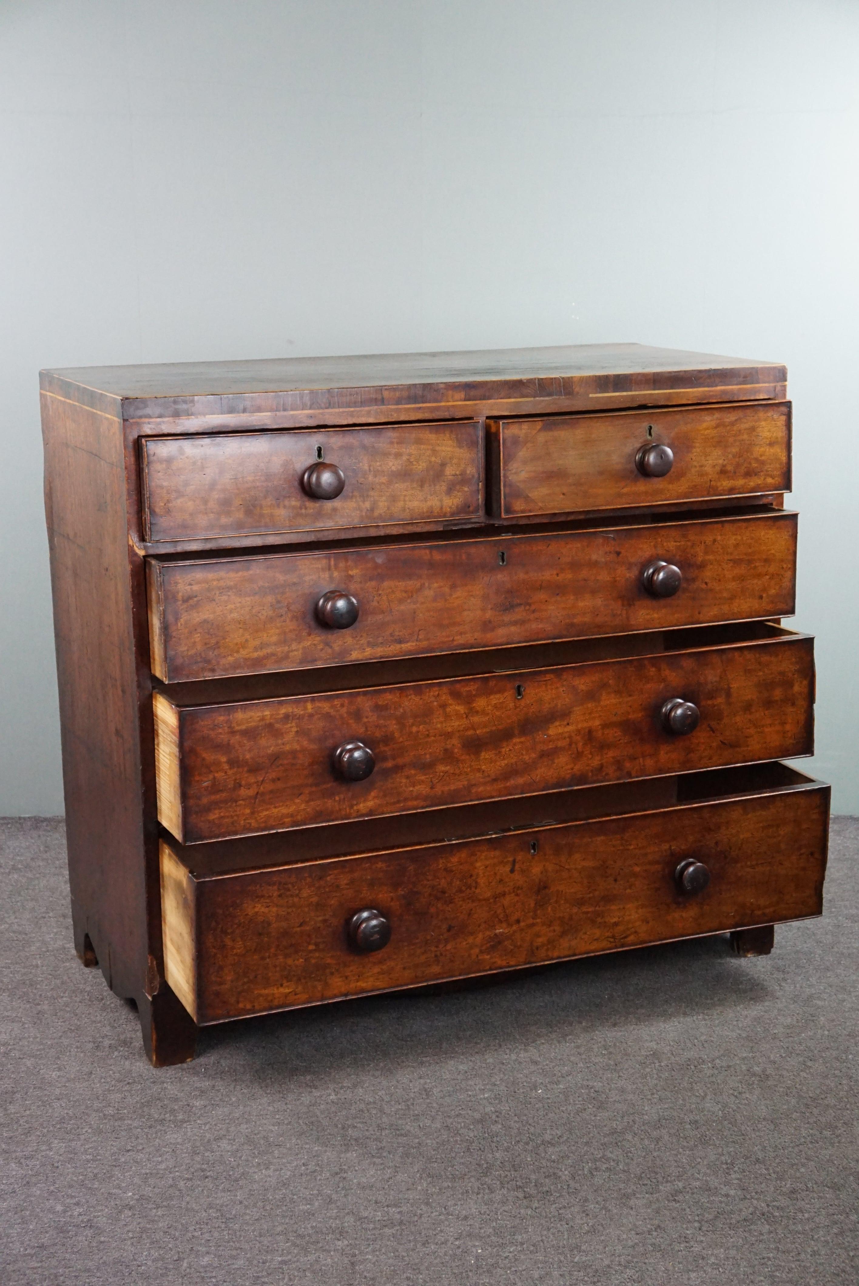 Offered is this robust antique English mahogany chest of drawers with 5 drawers from the mid-19th century, boasting a beautiful patina. 

We believe that every warm and cozy interior needs a beautiful antique chest of drawers. Not only for storing