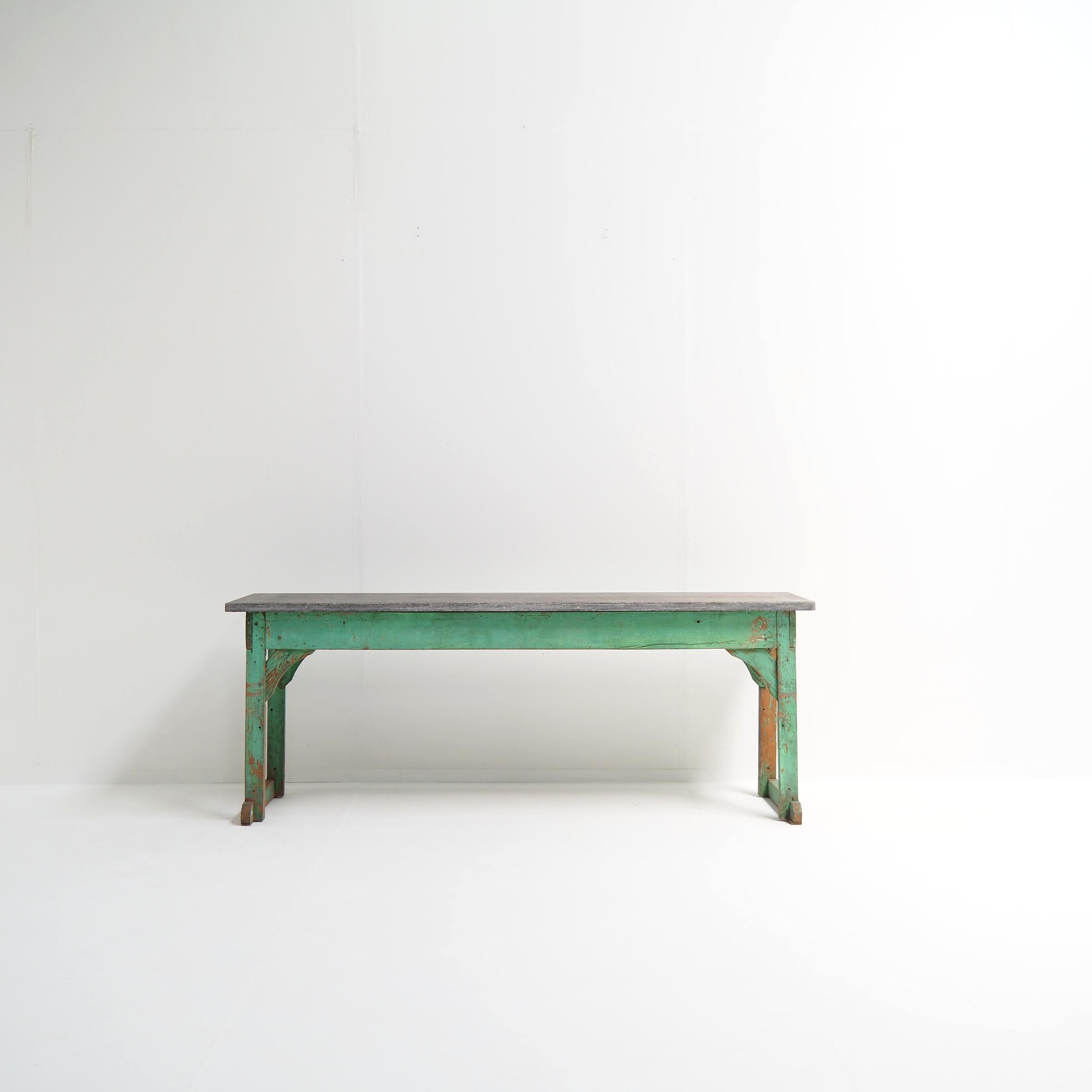 Un tavolino robusto con un alto valore decorativo. La base in legno presenta incastri a mortasa e tenone e una finitura laccata verde con un'attraente patina antica. La parte superiore in pietra blu presenta bellissimi fossili ed è leggermente