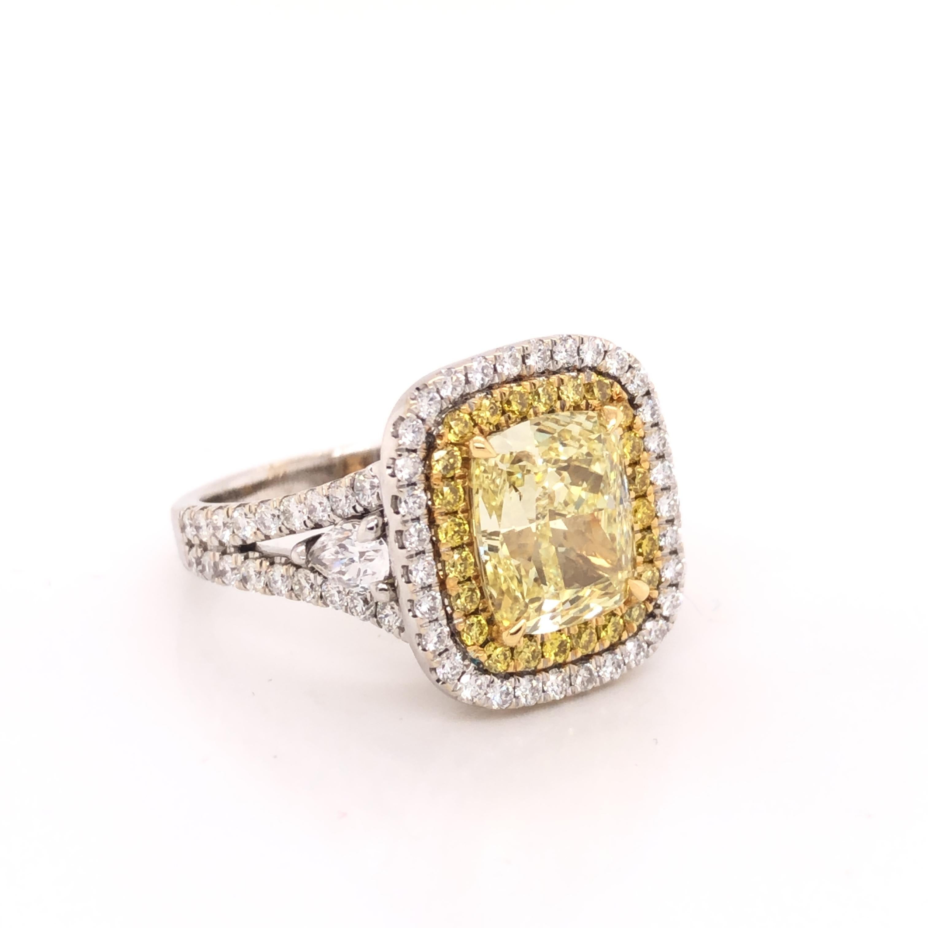 Beautifully hand crafted ring in 18k white gold. The focal point of the ring is one GIA certified fancy intense yellow cushion cut diamond. Fancy colored diamonds are extremely rare as the color grade fancy intense is the most sought after shade of