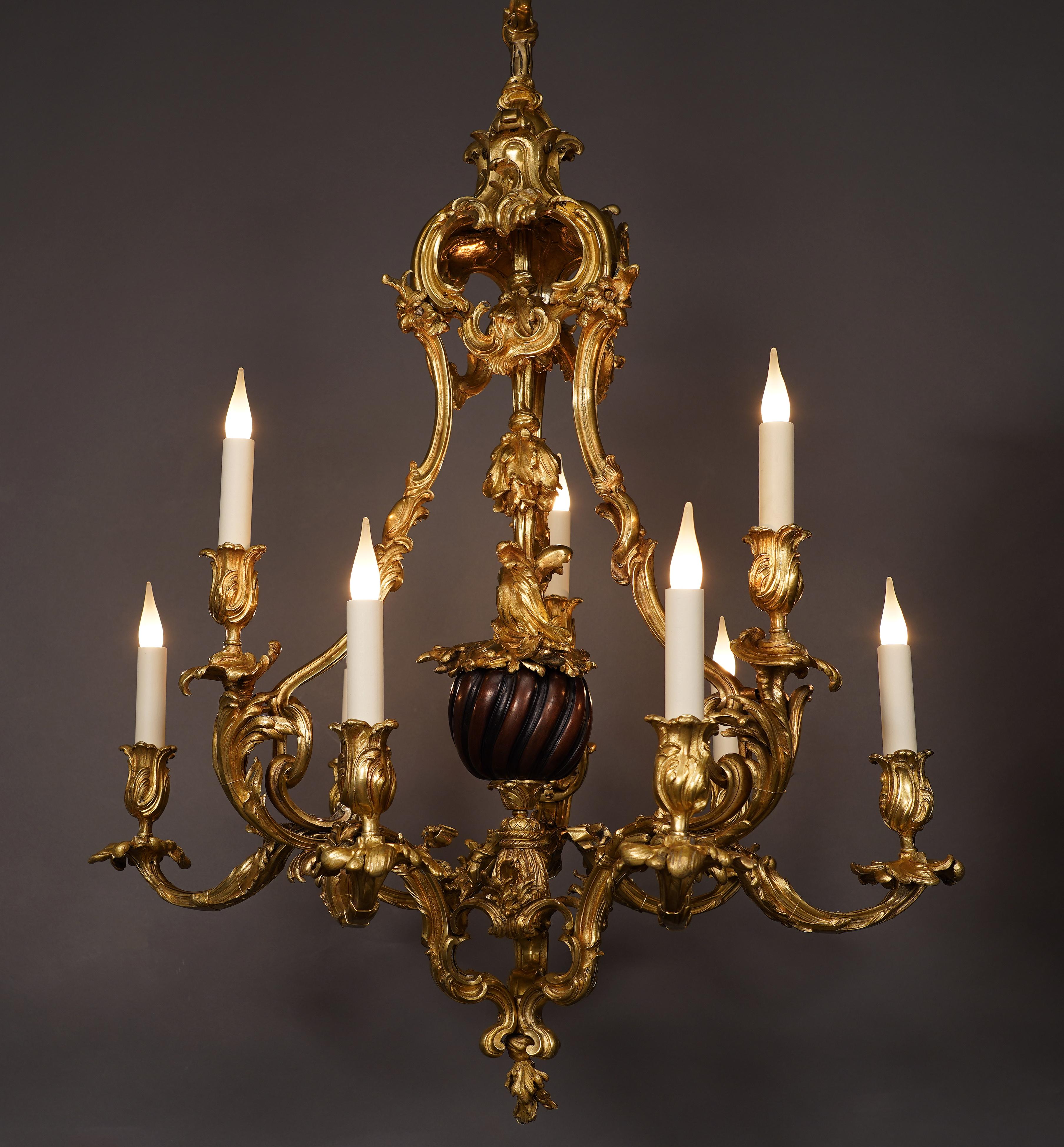 Beautiful Louis XV inspired chandelier in chiseled and gilded bronze with nine sconces. It consists of a baluster shaft decorated with a patinated bronze sphere with twisted fluting, surrounded by three uprights richly embellished with scrolls of