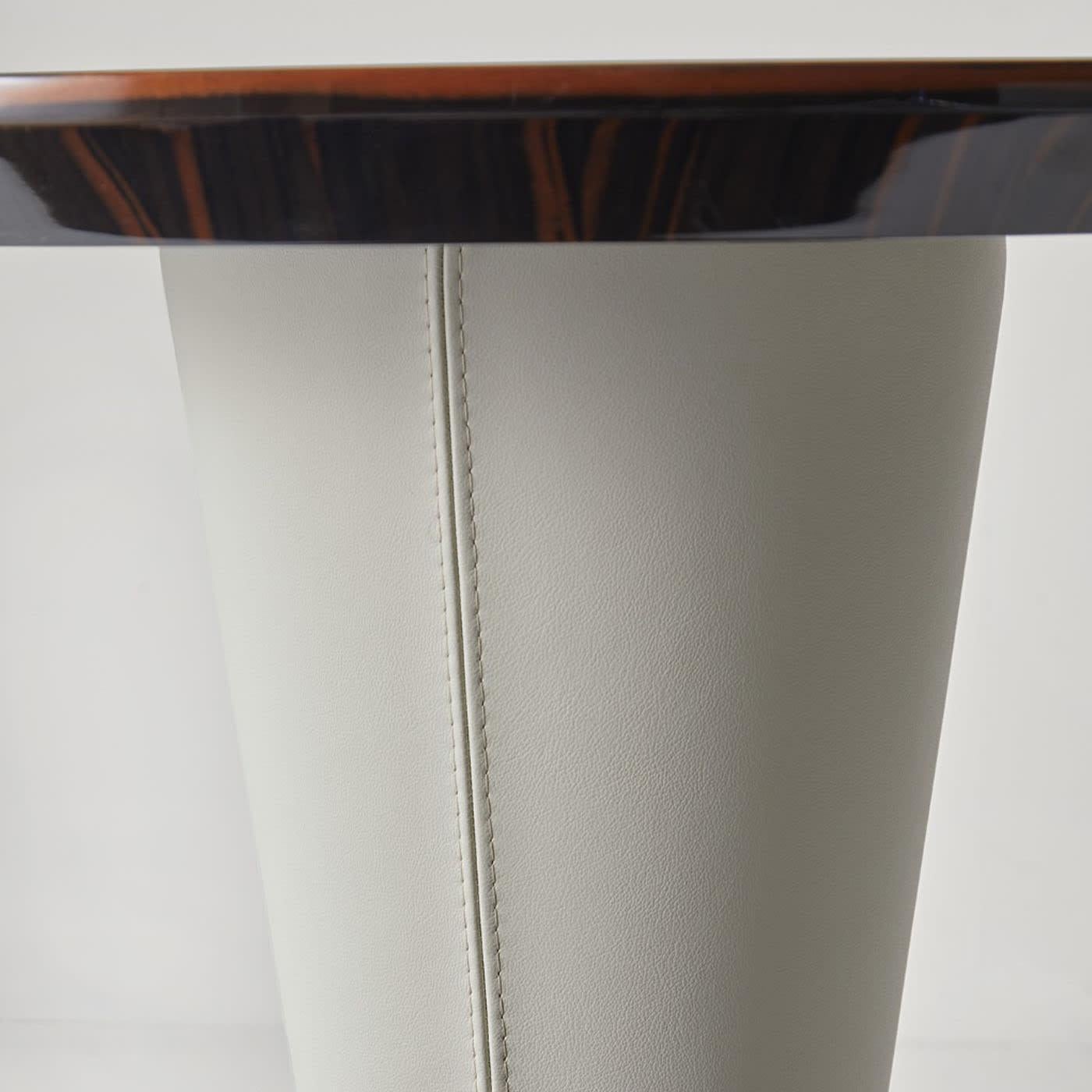 Rocchetto round side table with Ebano Macasar polished wooden top and padded leg in leather. A small jewel of all-Italian manufacturing.