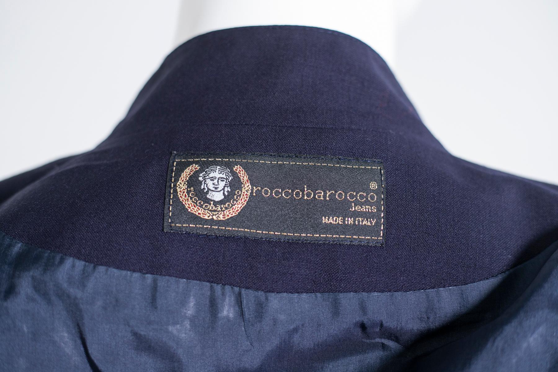 Belle veste courte bleu marine par Rocco Barocco Jeans. La veste est 100% laine et à l'intérieur se trouve l'étiquette Made in Italy. Ligne très élégante, rappelant les vestes des années 80 avec le rembourrage sur l'épaule. Sur le devant, le logo
