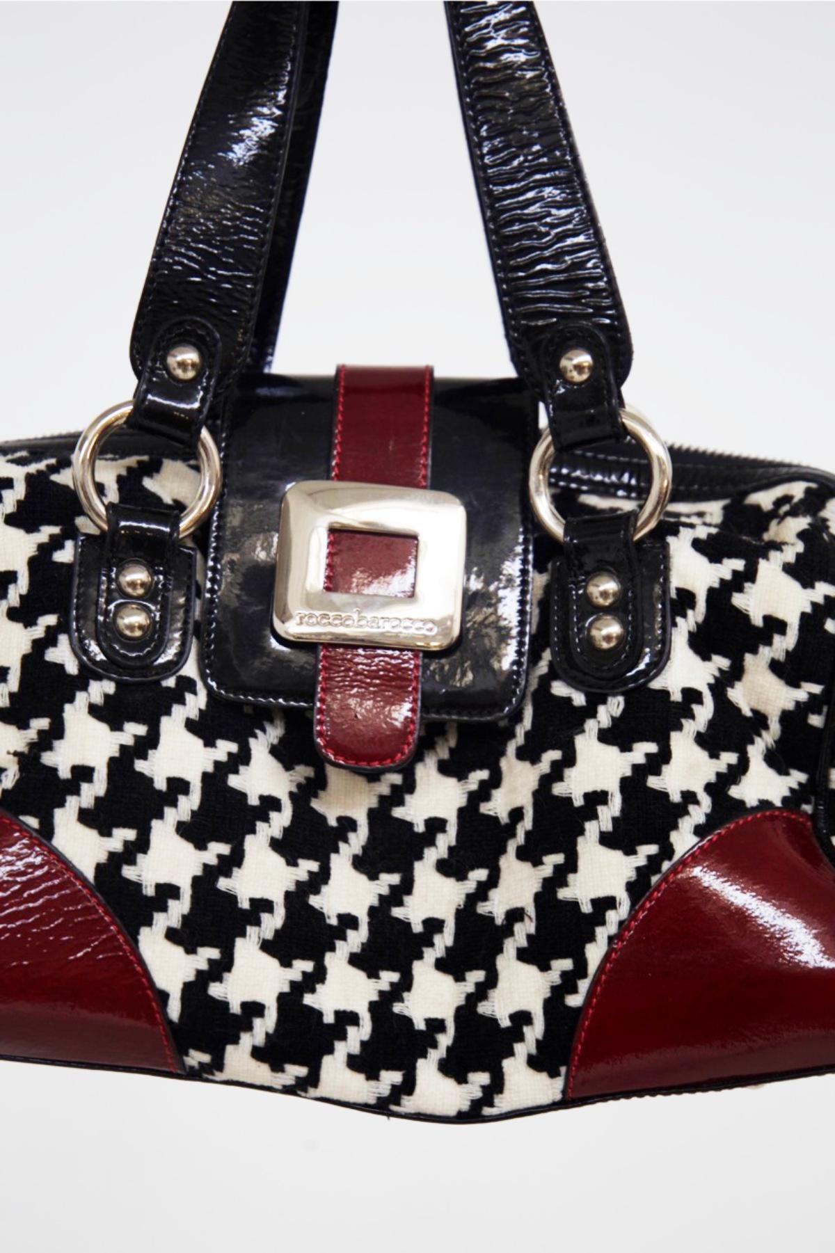 Vintage bag in patent leather and fabric designed by Rocco Barocco in the 1990s, made in Italy.
The bag has a stiffer base with the two corners in red patent leather, the rest of the body is composed of black and white houndstooth fabric,