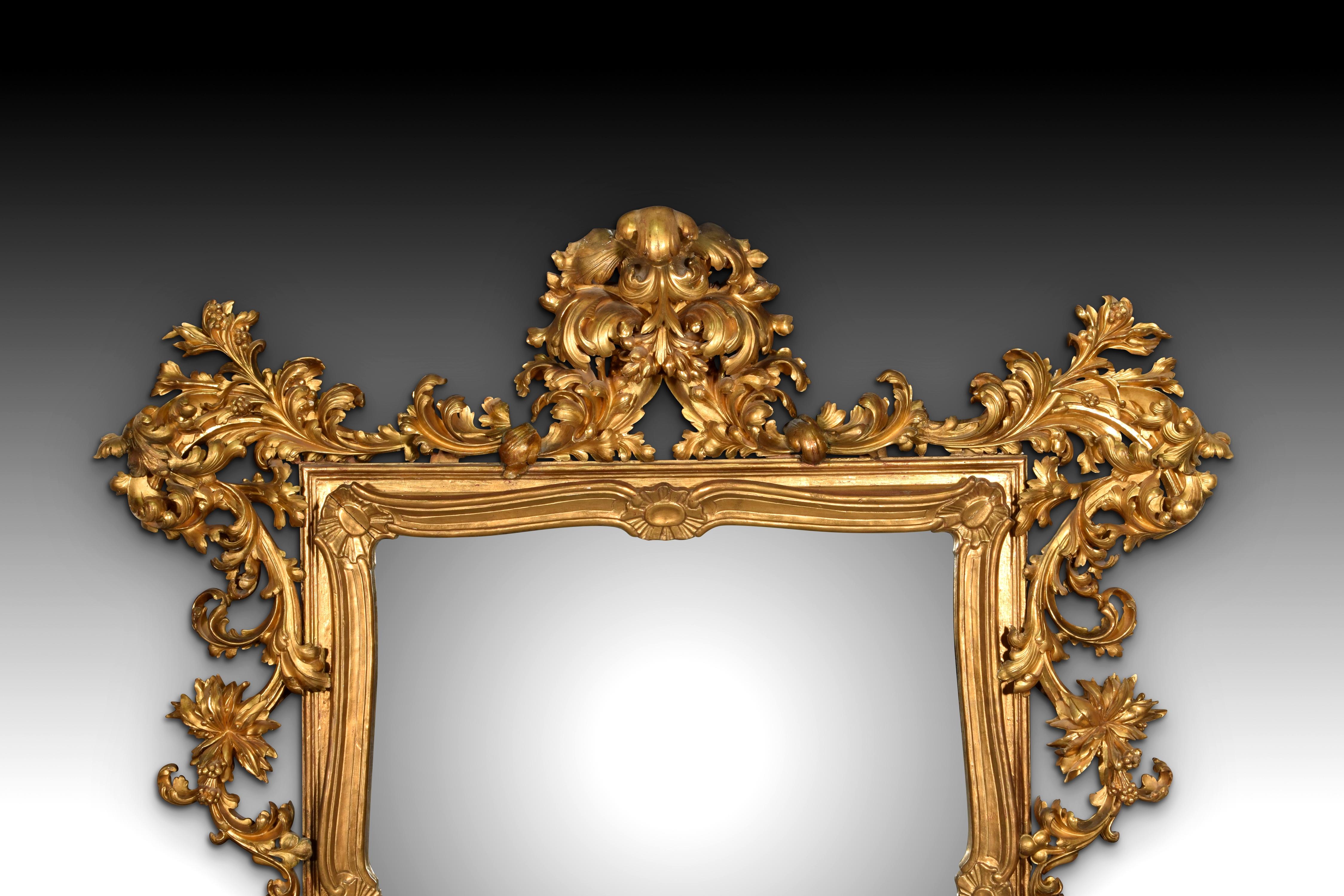 Specchio in stile rococò. Legno intagliato e dorato. XIX secolo.
 Specchio leggermente rettangolare con cornice in legno intagliato e dorato e decorato con elementi ispirati all'arte rococò del XVIII secolo (ciottoli, curve e controcurve, elementi