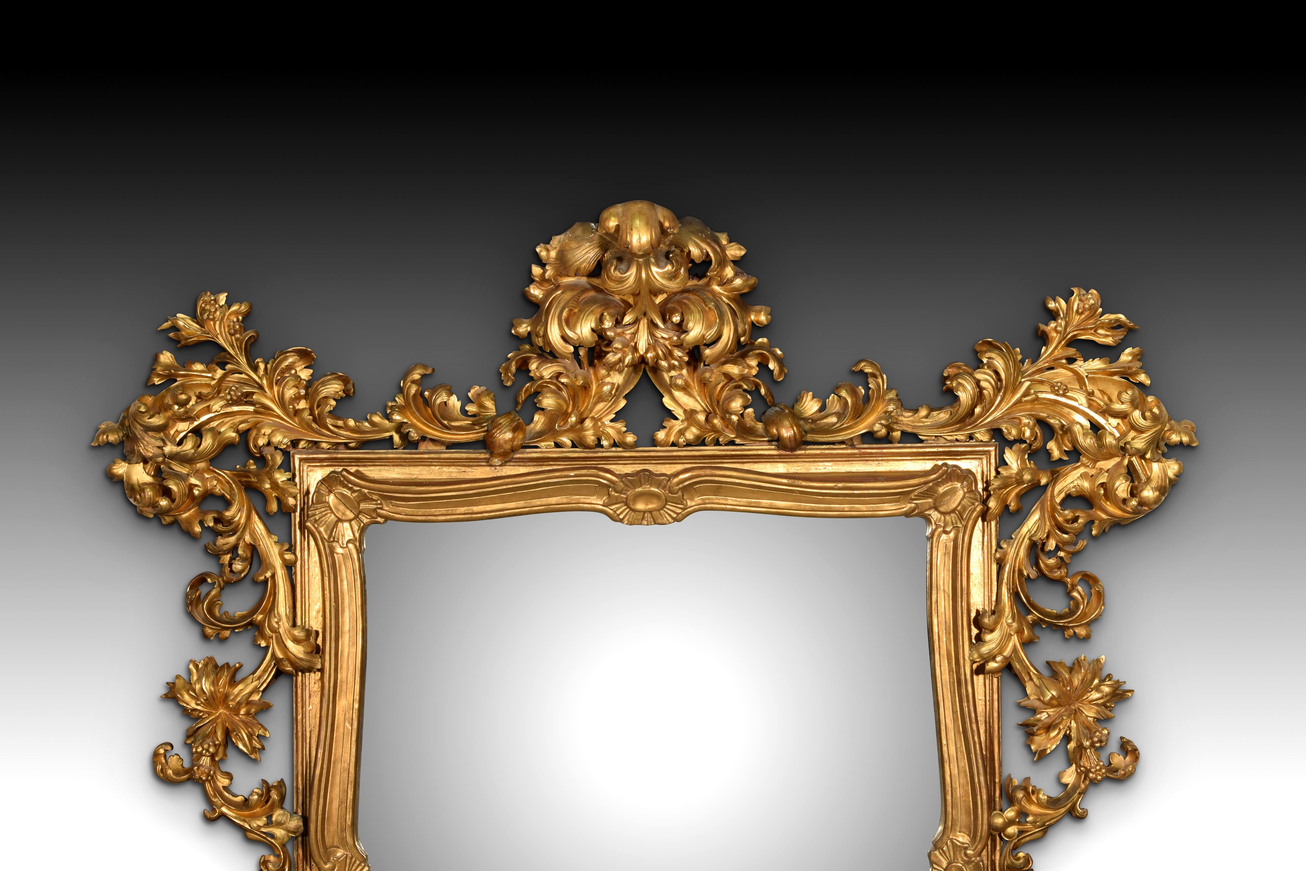 Rococo style mirror. Carved and gilded wood. XIX century.
 Slightly rectangular mirror with a frame made of carved and gilded wood and decorated with elements inspired by 18th-century Rococo art (pebbles, curves and counter-curves, fleshy plant