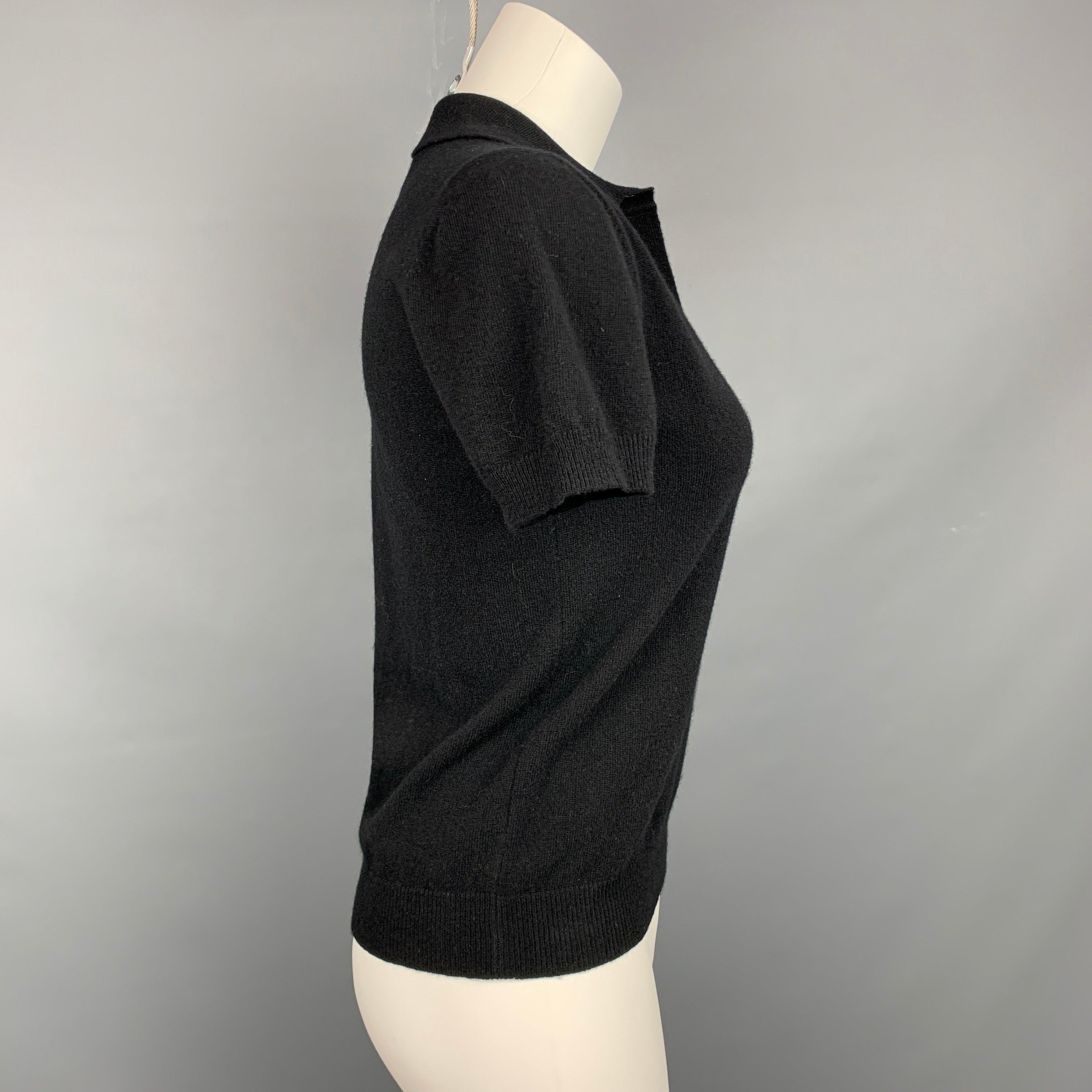 Le polo Rochas se présente en laine noire avec un détail d'embellissement 