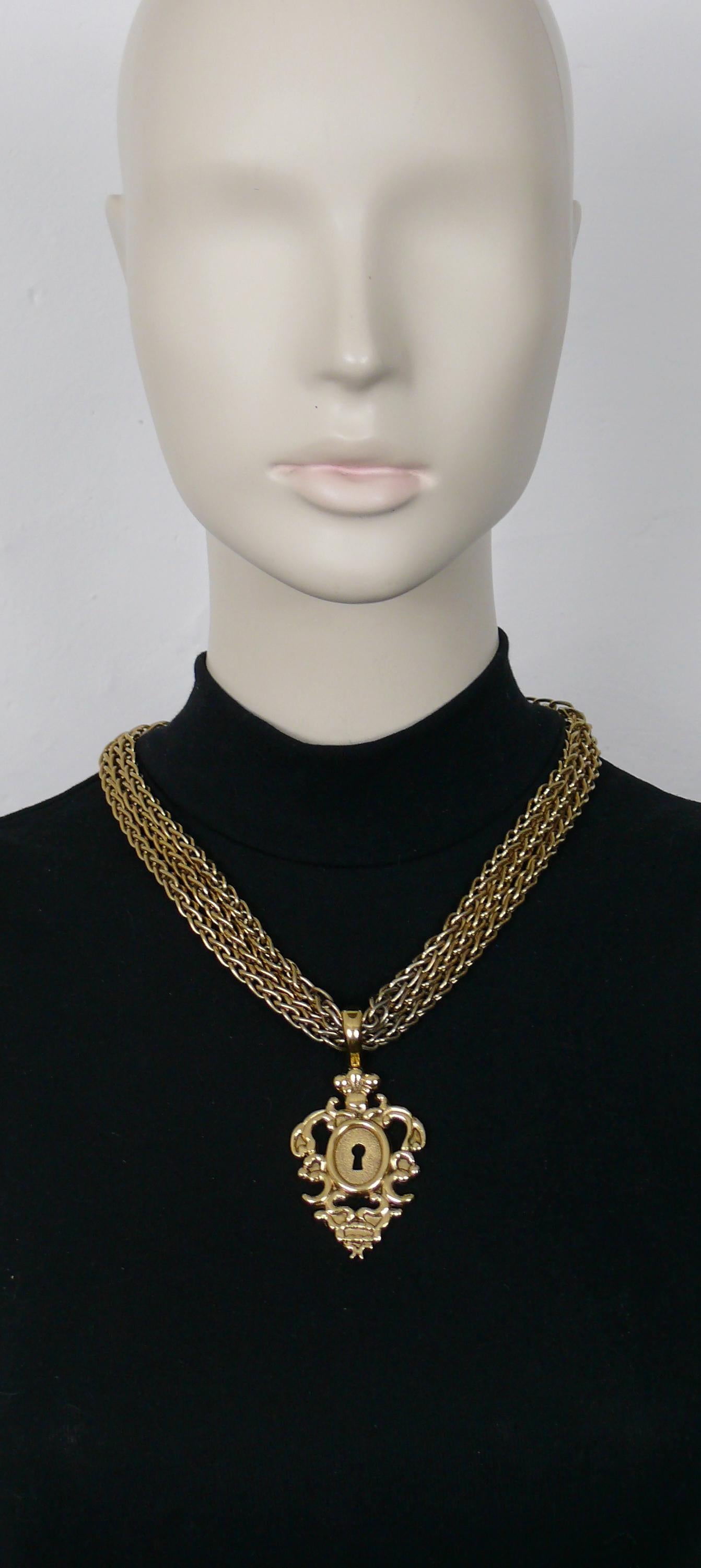 ROCHAS Vintage-Halskette mit goldfarbener Dreifachkette und einem ikonischen Anhänger im Barockschloss-Design.

Auf der Rückseite des Schlosses ist ROCHAS 882 eingeprägt.

T-Bar und Knebelverschluss.

Ungefähre Maße: tragbare Länge ca. 52 cm (20,47