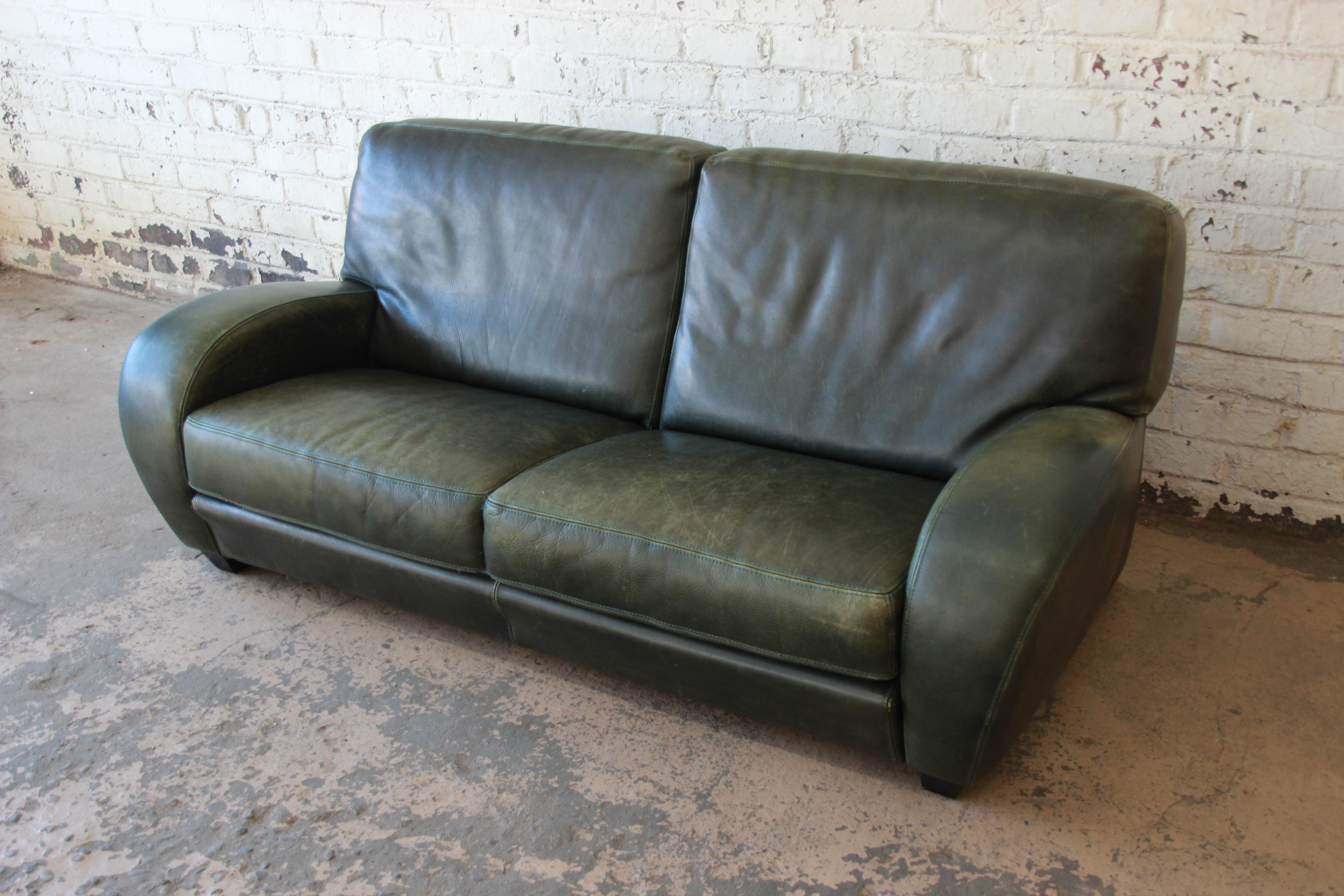 A gorgeous Art Deco style leather sofa by Roche Bobois. The sofa offers soft high-grade leather in army green. The leather is beautifully worn from age, with a nice patina. The sofa is extremely comfortable. It is in good vintage condition and ready