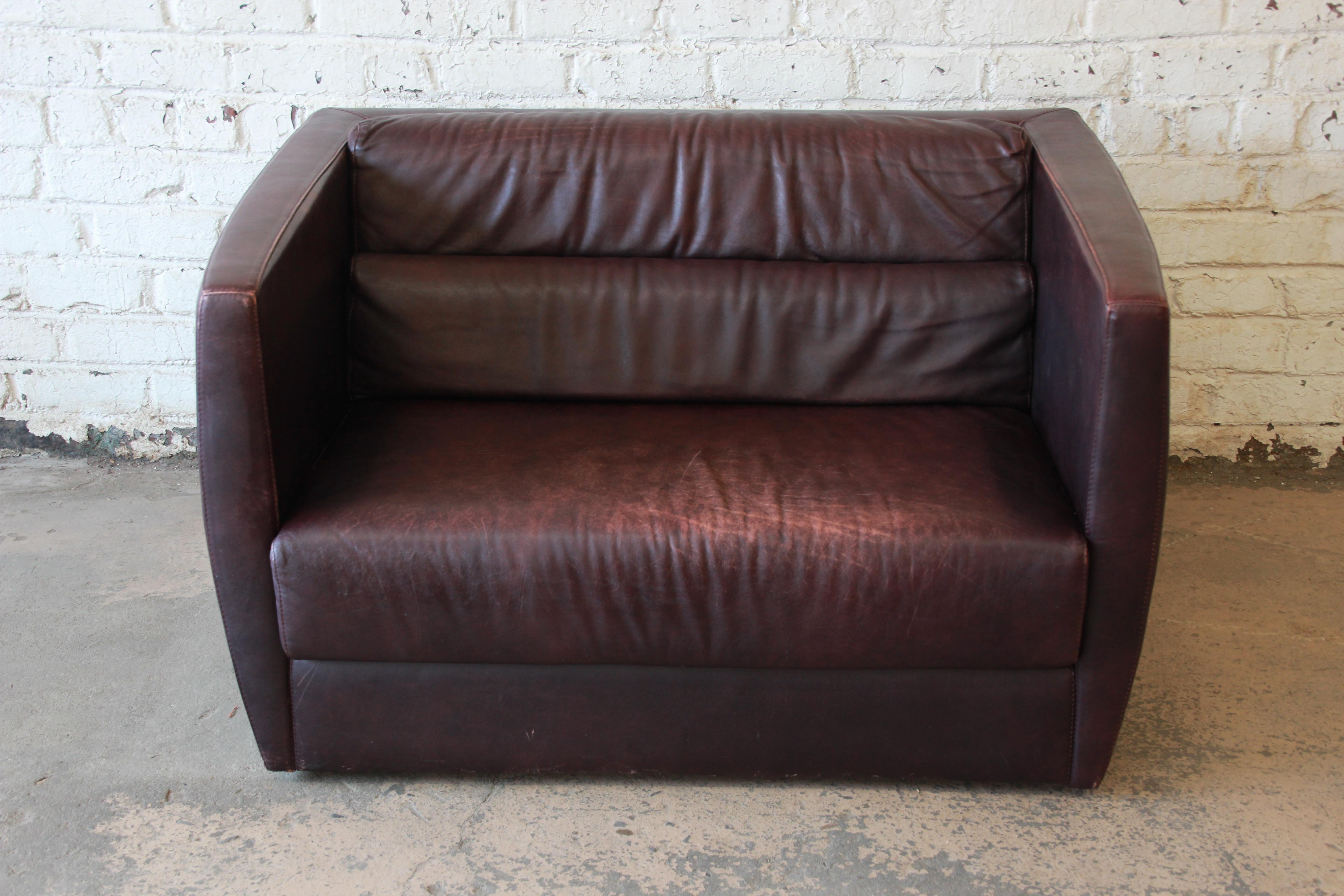 An exceptional Bauhaus style leather love seat or oversized chair by Roche Bobois. The love seat features gorgeous high-end leather in a deep burgundy, with a nice patina that only adds to the character and age of the piece. It has a sleek and