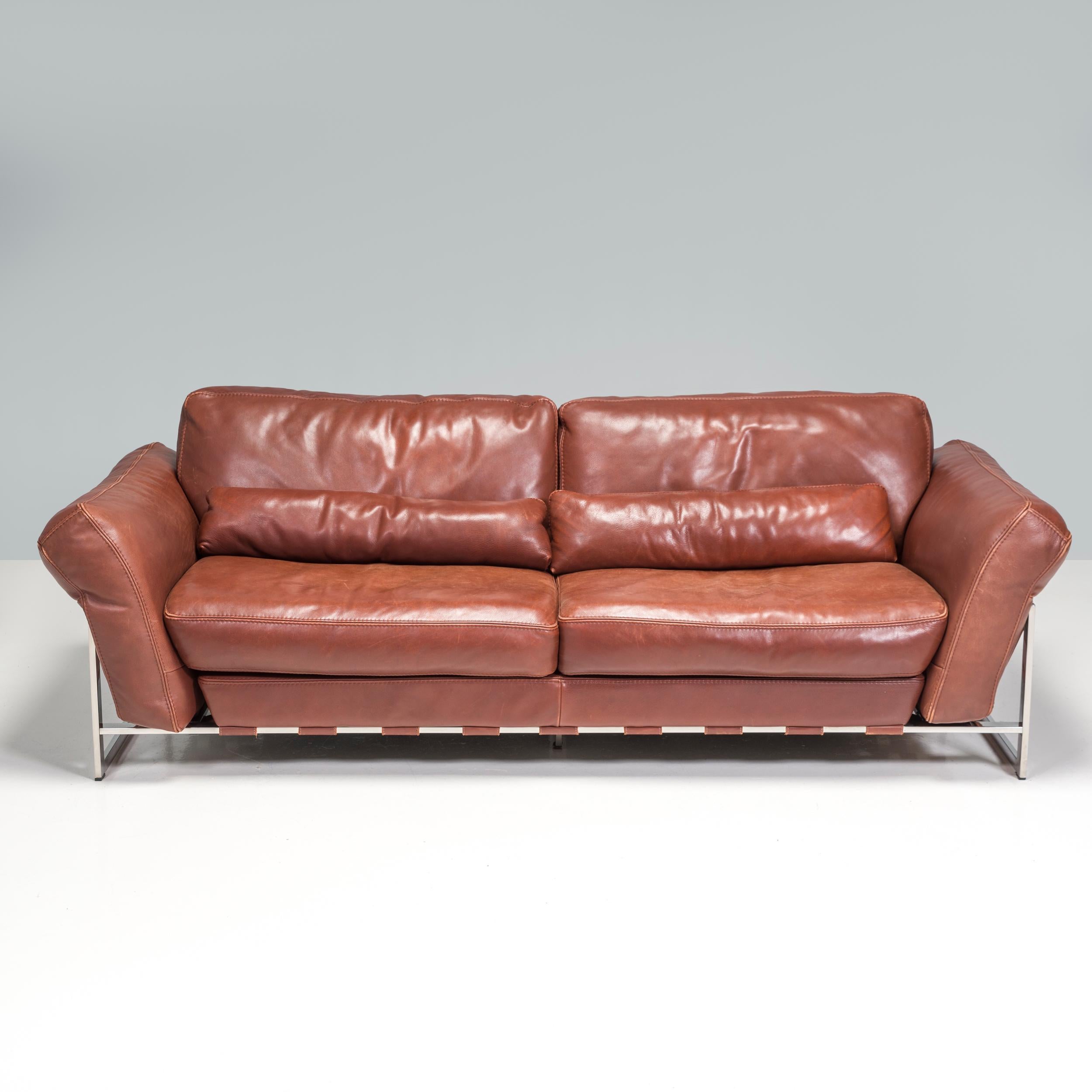 Conçu et fabriqué par Roche Bobois, ce canapé est l'équilibre parfait entre confort et style.

Doté d'une structure angulaire en chrome poli, le canapé est équipé d'un cerclage en cuir marron contrastant qui crée la structure nécessaire au maintien