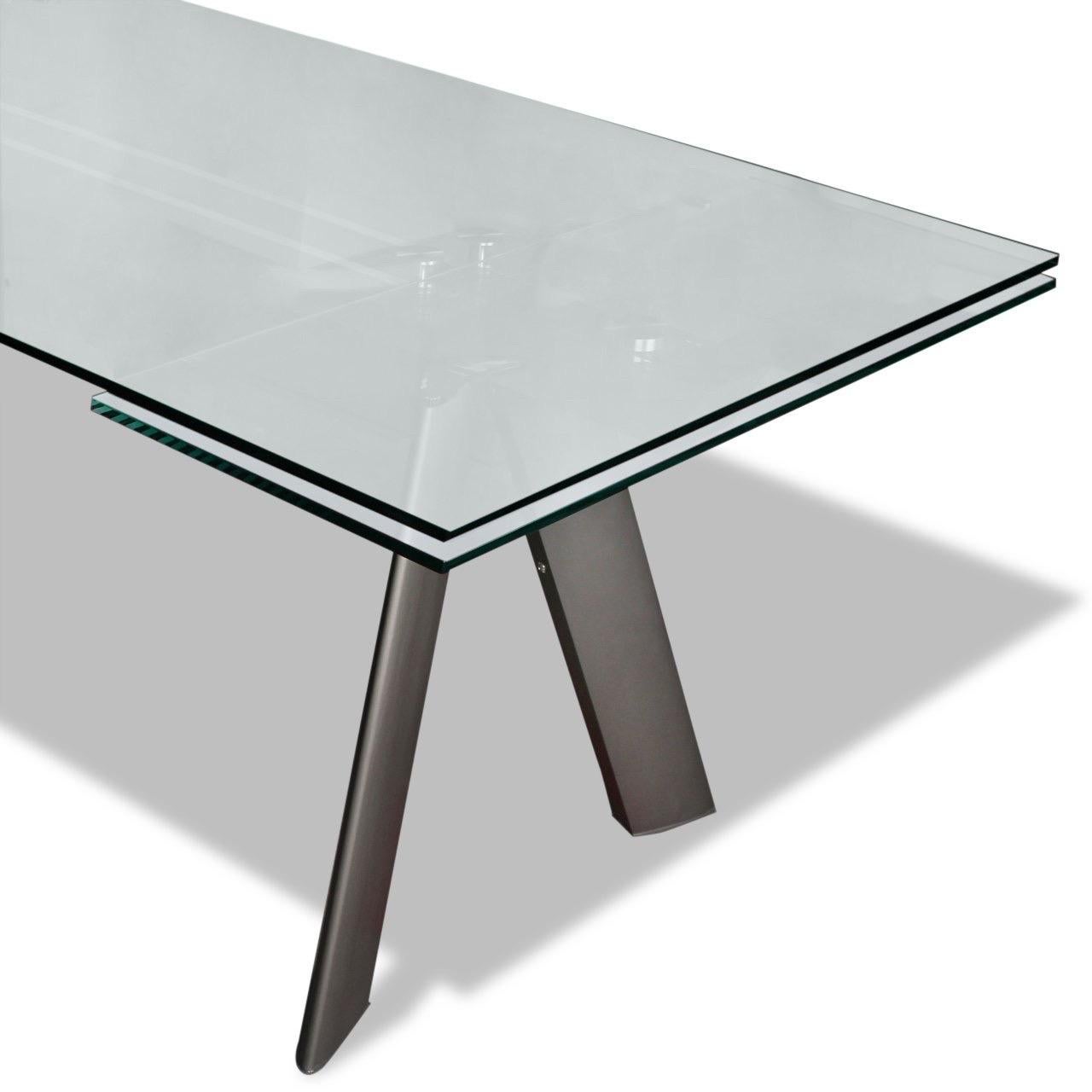 Table de salle à manger Chronos conçue par Giusi Mastro pour Roche-Bobois.

Le plateau en verre trempé est posé sur une structure et un piètement en aluminium poli et brillant, complété par des pieds en croûte de cuir.

La table est également dotée