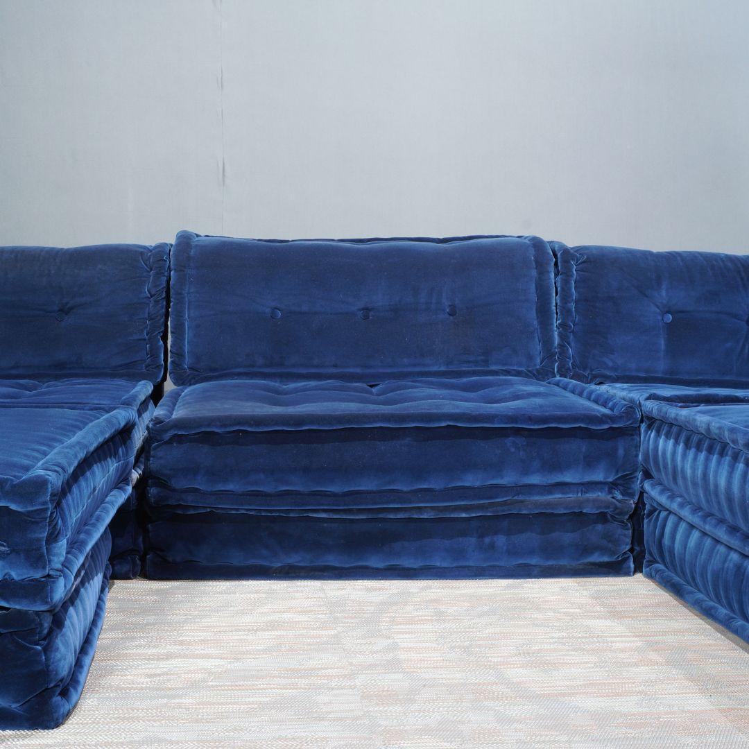 The Roche Bobois Mah Jong Sofa, a design icon by Hans Hopfer, epitomises modular versatility and luxurious comfort. This particular set of 12 is upholstered in plush cotton velvet, providing a sumptuous, tactile experience. The deep, midnight blue
