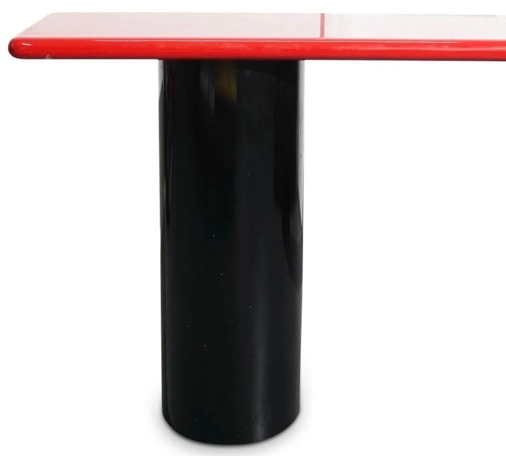 Roche Bobois Memphis style console table composed of wood with red lacquered, rounded edge top, cylindrical black lacquered base, and an overall unique slanted design.