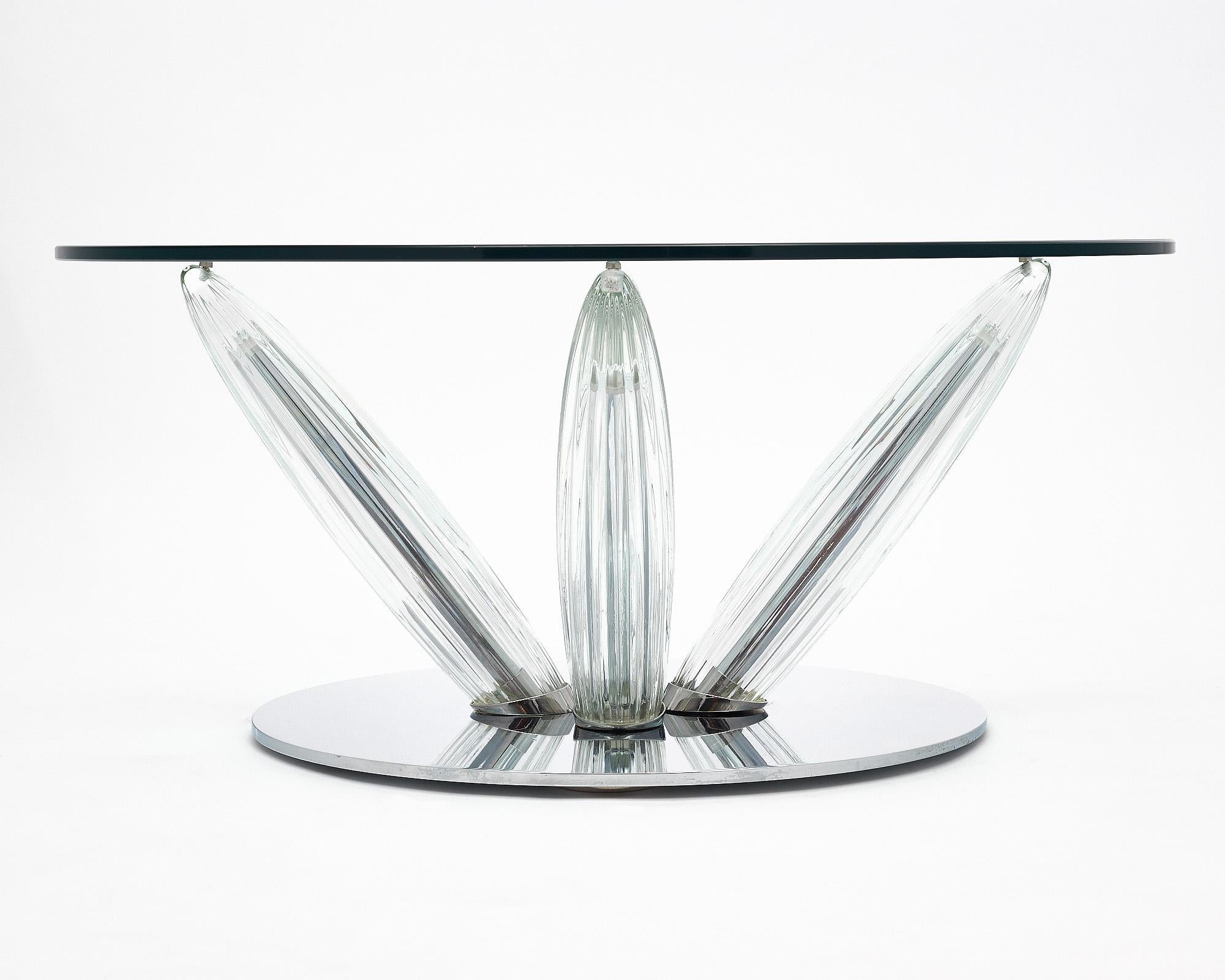 Coffee table from France made by iconic brand Roche Bobois. This piece has a glass circular top that sits supported by four thick glass covered legs that taper down to a chrome circular base. The glass is signed.
