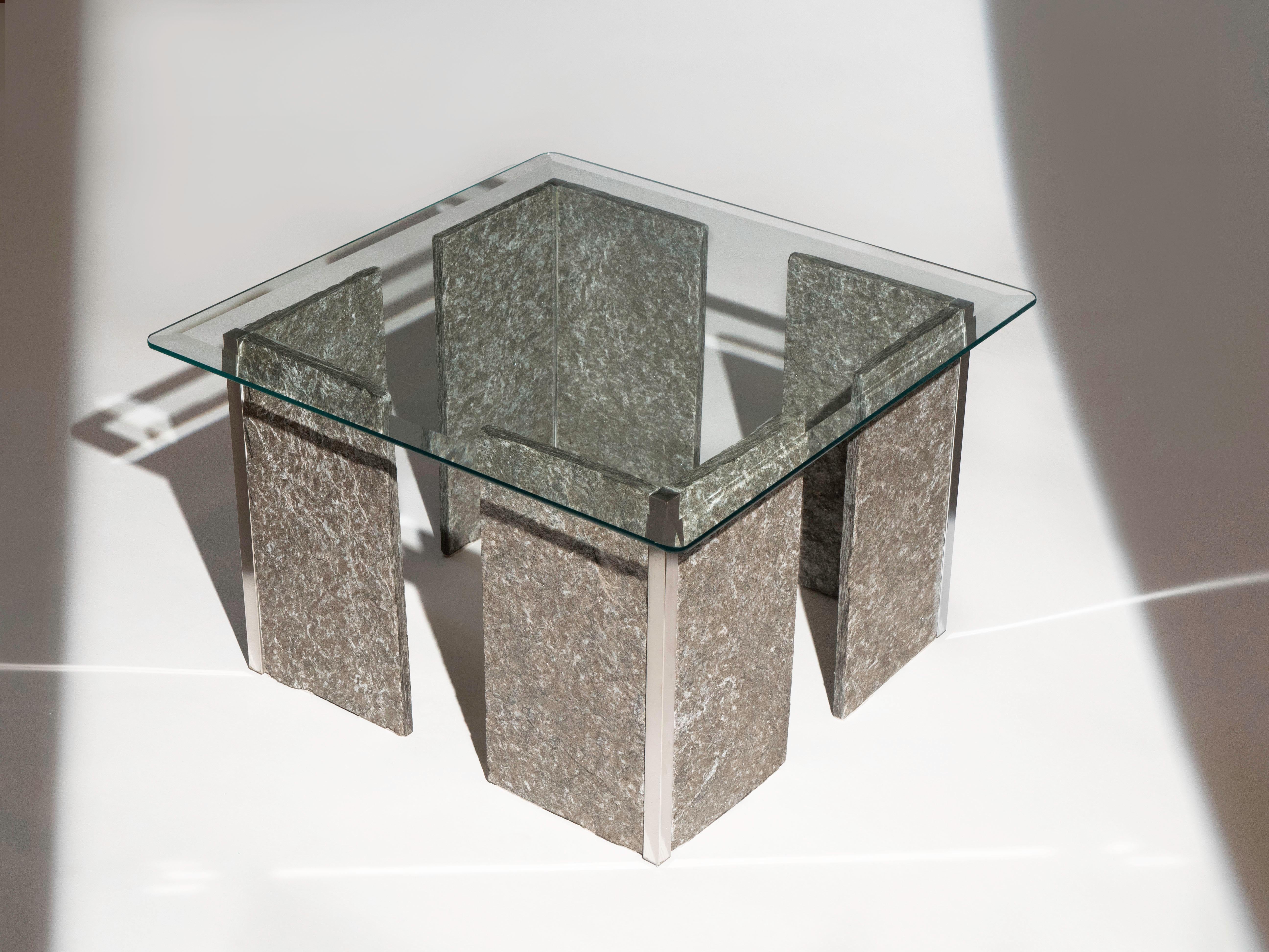 Glass coffee table with a slate grey stone base with chrome accented corners by Roche Bobois, circa 1970's. The stone has a beautiful light grey/white veining as well as a faint translucent blue veining shown when light hits it directly.

It is in