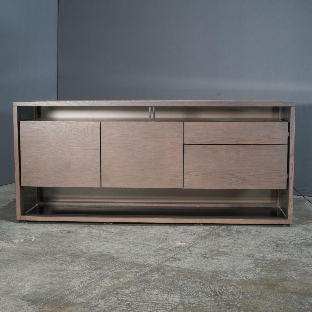 Le buffet Glassbox de Roche Bobois en anthracite et verre fumé allie élégance moderne et design fonctionnel. Fabriquée avec un cadre anthracite élégant et dotée de portes en verre fumé, cette pièce crée un effet visuel saisissant qui met en valeur